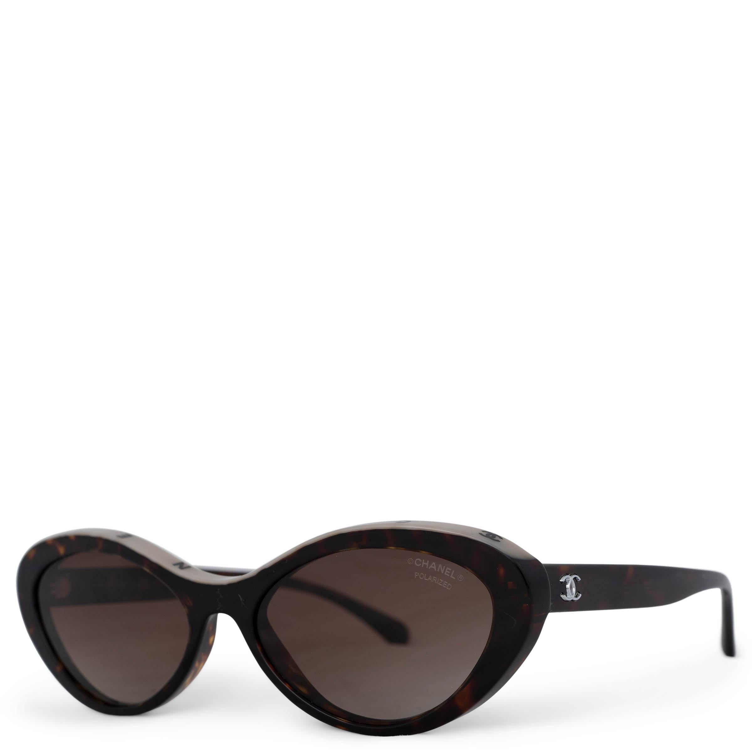 These 100% authentic Chanel 5416 oval cat-eye sunglasses are crafted in a brown and amber Tortoise design, accented with a beige border on top and black Chanel logo lettering. They feature a subtle silver-tone CC logo on the temples and are