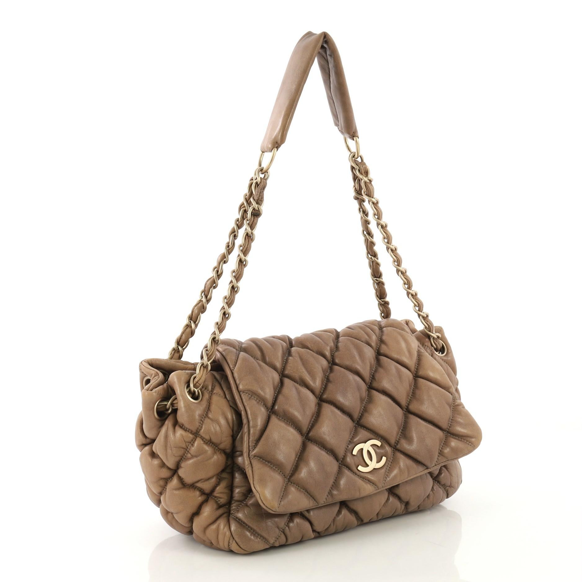This Chanel Bubble Accordion Flap Bag Quilted Lambskin Medium, crafted in brown quilted lambskin, features woven-in leather chain strap threaded through eyelets cinching its sides, CC logo at its flap, and matte gold-tone hardware. Its magnetic snap