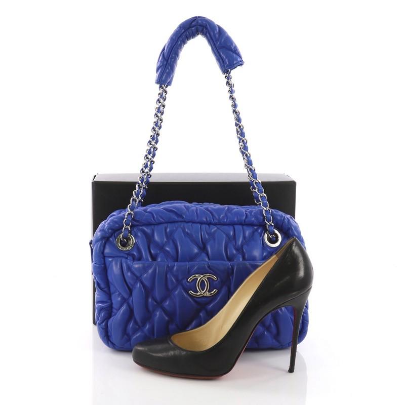 This Chanel Bubble Camera Bag Quilted Lambskin Small, crafted in blue quilted lambskin, features woven in leather chain link straps with leather pads, exterior slip pocket, and silver-tone hardware. Its zip closure opens to a blue fabric interior