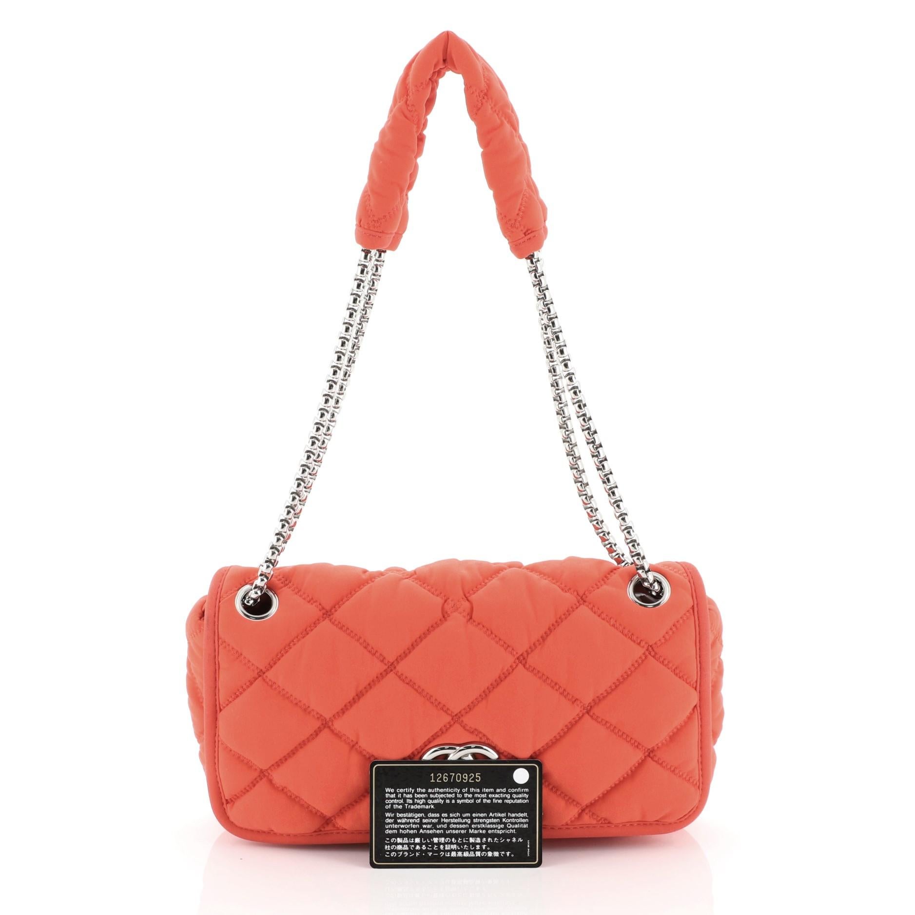 This Chanel Bubble Flap Bag Quilted Nylon Medium, crafted in red quilted nylon, features a woven-in nylon chain link strap, Chanel's CC logo at the front and silver-tone hardware. Its flap opens to a gray satin interior with side zip pocket.