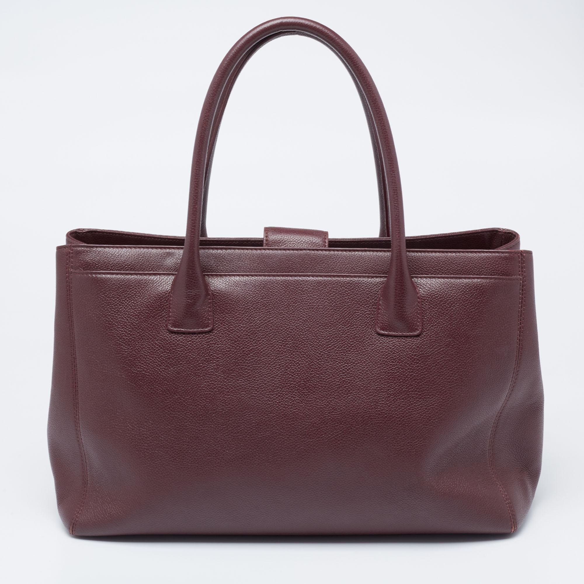 This Cerf tote from Chanel is a perfect blend of function and style. It features a burgundy leather construction that is enhanced with a metal CC logo on the front and dual top handles. It is equipped with a spacious interior that can easily hold