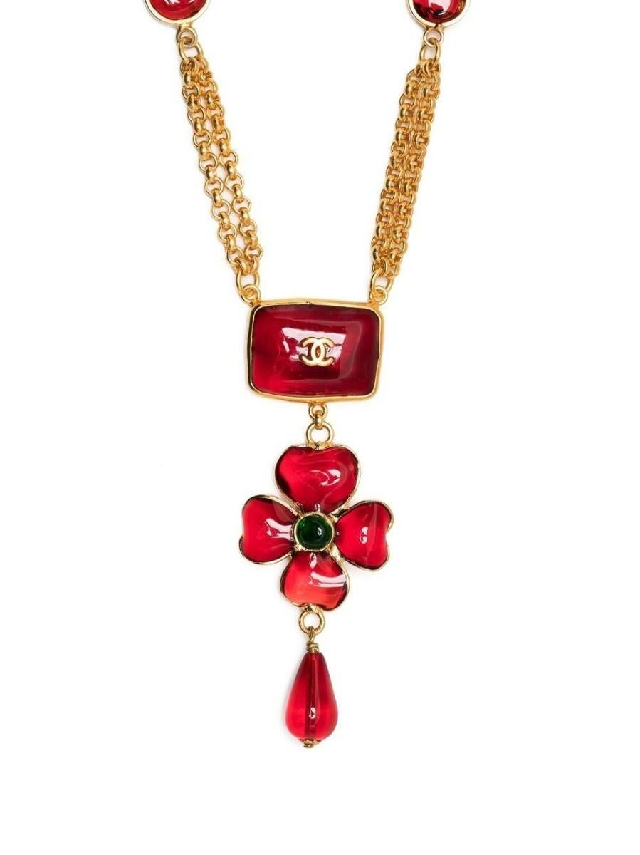 Designed by Gripoix for Chanel, this unique vintage necklace displays 2 strands of gold-toned chains with burgundy flower motifs and two small square motifs. The focus of the necklace is red bead hanging from a flower with green glass centre and a