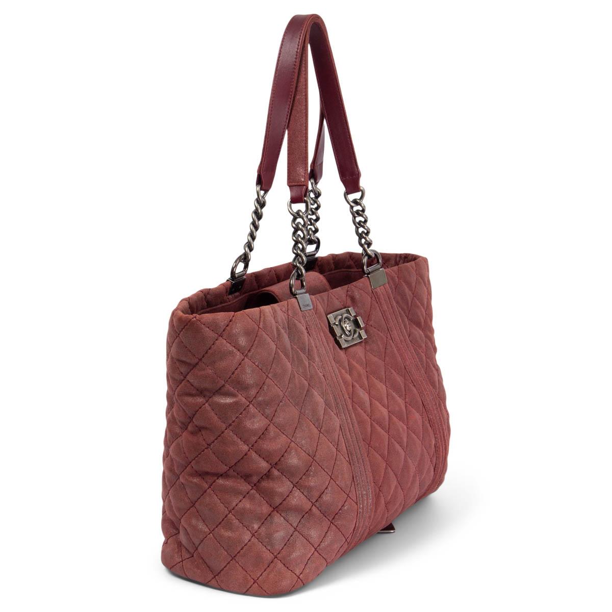 100% authentic Chanel Gentle Boy quilted large shopping tote in distressed shimmery burgundy calfskin. The bag features ruthenium chain link strap handles with leather shoulder pads and a ruthenium Chanel CC press lock. Opens the top to a burgundy