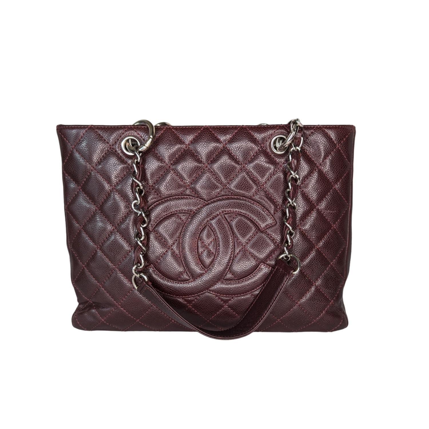 This stylish tote is crafted of diamond-quilted caviar leather in burgundy. This shoulder bag features leather-threaded polished silver chain-link shoulder straps with shoulder pads, a quilted Chanel CC logo on the front, and a flat pocket on the