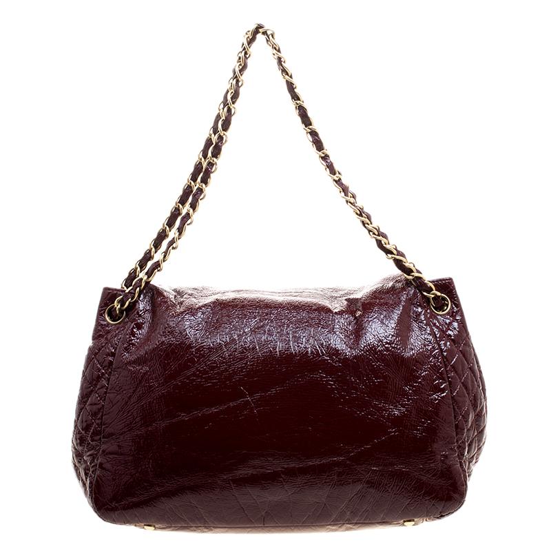 This Timeless Accordion Flap bag from the house of Chanel is designed in a gorgeous burgundy shade in a quilted detail patent leather. It comes with the 'CC' stitch detail and fitted with a chain and leather entwined shoulder handle. The plush