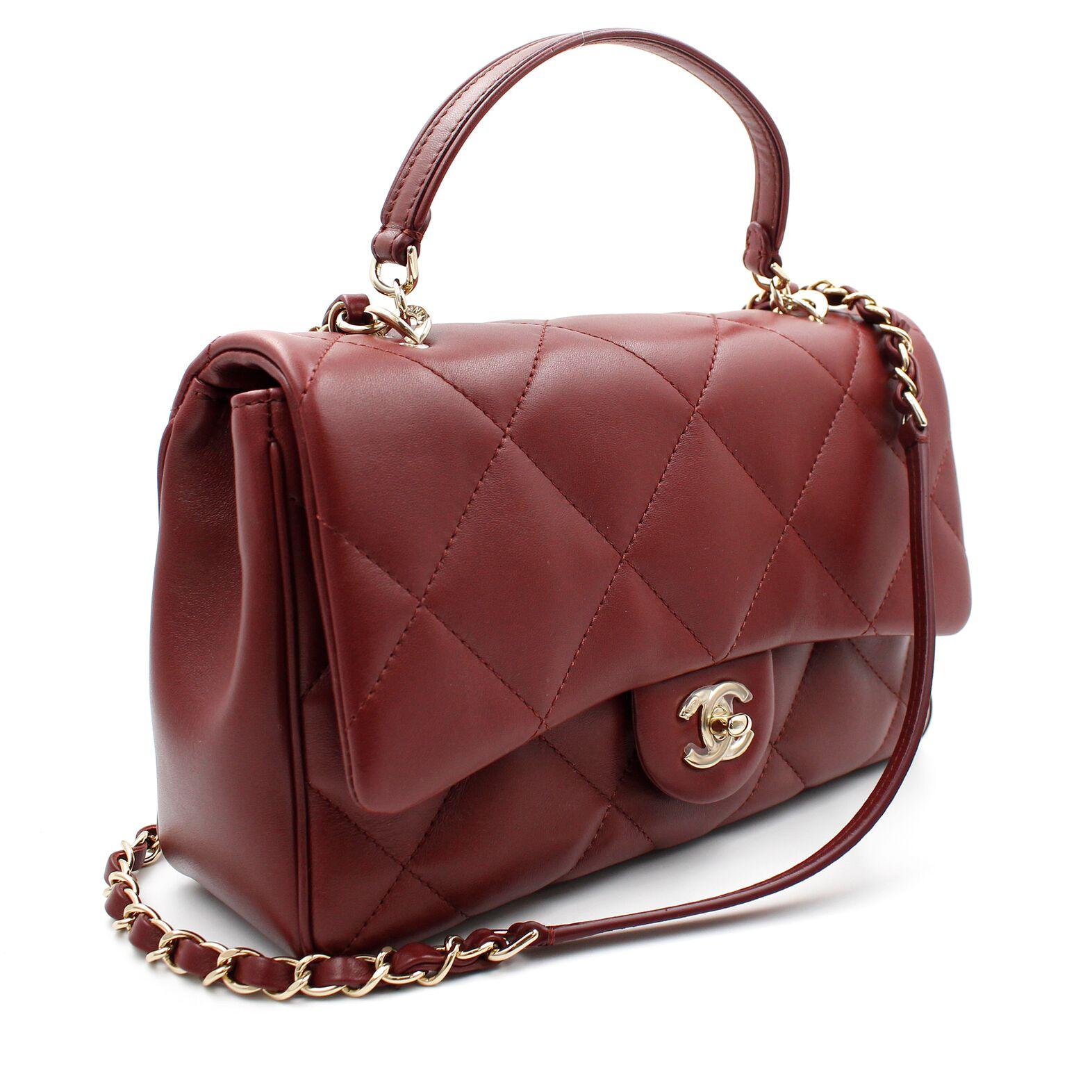 New Chanel Medium Classic Flap Bag in burgundy lambskin leather with gold tone hardware. This bag features a front flap with signature CC turn-lock closure with an interwoven gold tone chain link with burgundy leather shoulder/cross-body strap.The