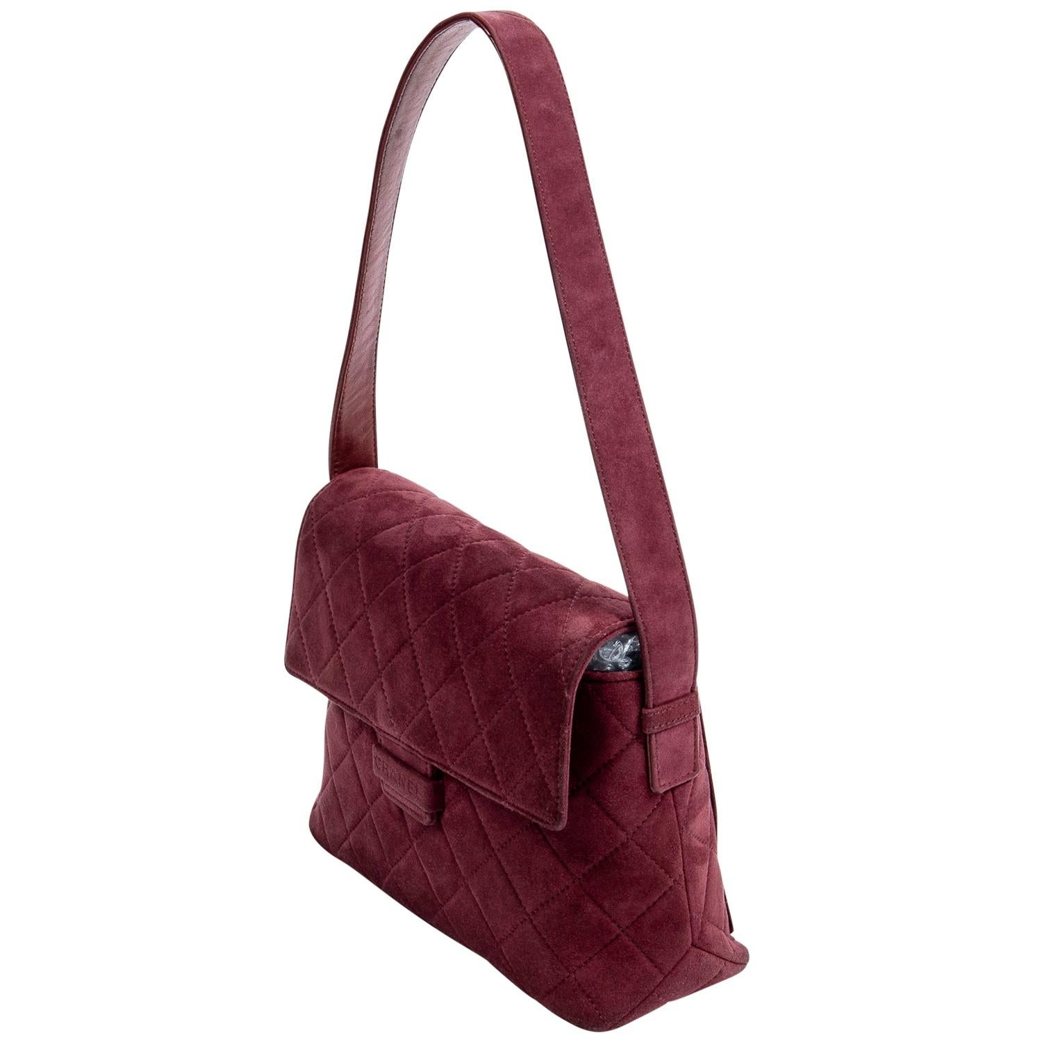 Stunning late 90s vintage treasure crafted of maroon quilted suede, with gold-tone hardware, a tonal leather trim, a single shoulder strap, and an exterior slip pocket on the back The CHANEL logo on the front is perfectly discrete and the pull