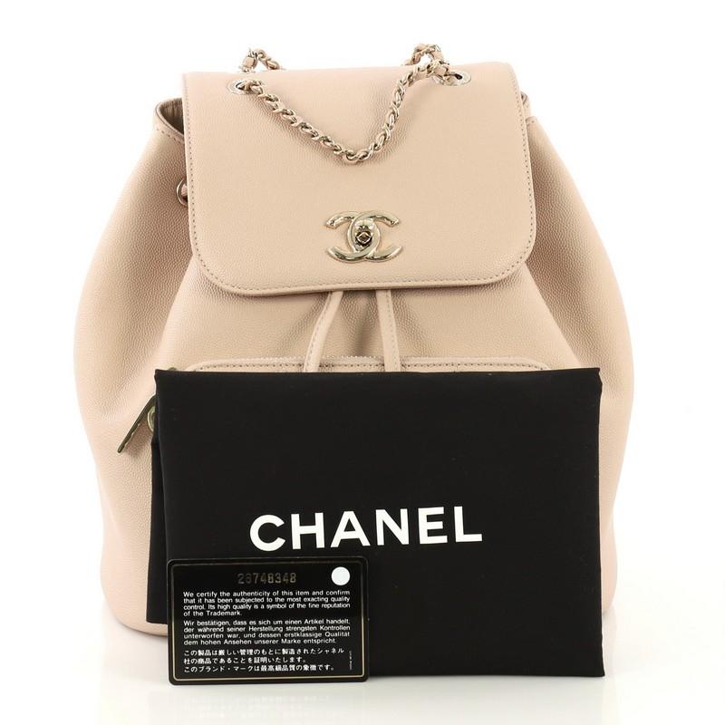 This Chanel Business Affinity Backpack Caviar Small, crafted from pink and neutral caviar leather, features woven-in leather chain top handle, dual leather straps, flap top with CC turn-lock closure, front zip pocket, and gold-tone hardware. Its