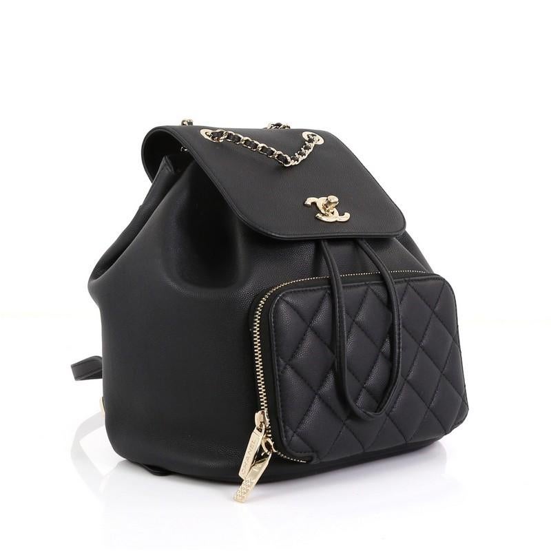 This Chanel Business Affinity Backpack Caviar Small, crafted from black caviar leather, features woven-in leather chain top handle, dual leather straps, flap top with CC turn-lock closure, front zip pocket, and gold-tone hardware. Its drawstring