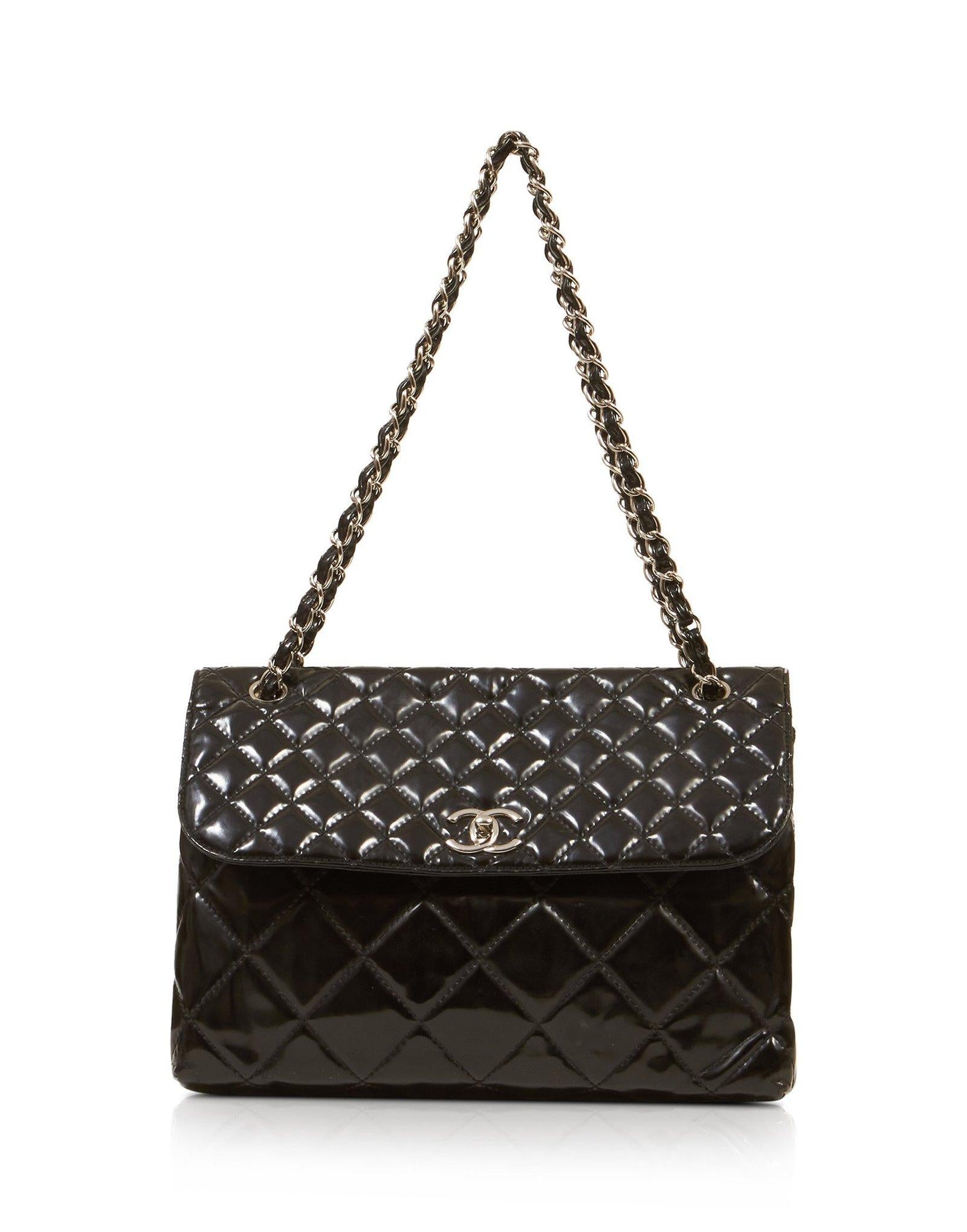 This business flap maxi shoulder bag is made of large diamond shaped quilted patent leather. The bag features silver chain link shoulder straps threaded with leather and a silver Chanel CC Mademoiselle turn lock. This flap opens to a fabric