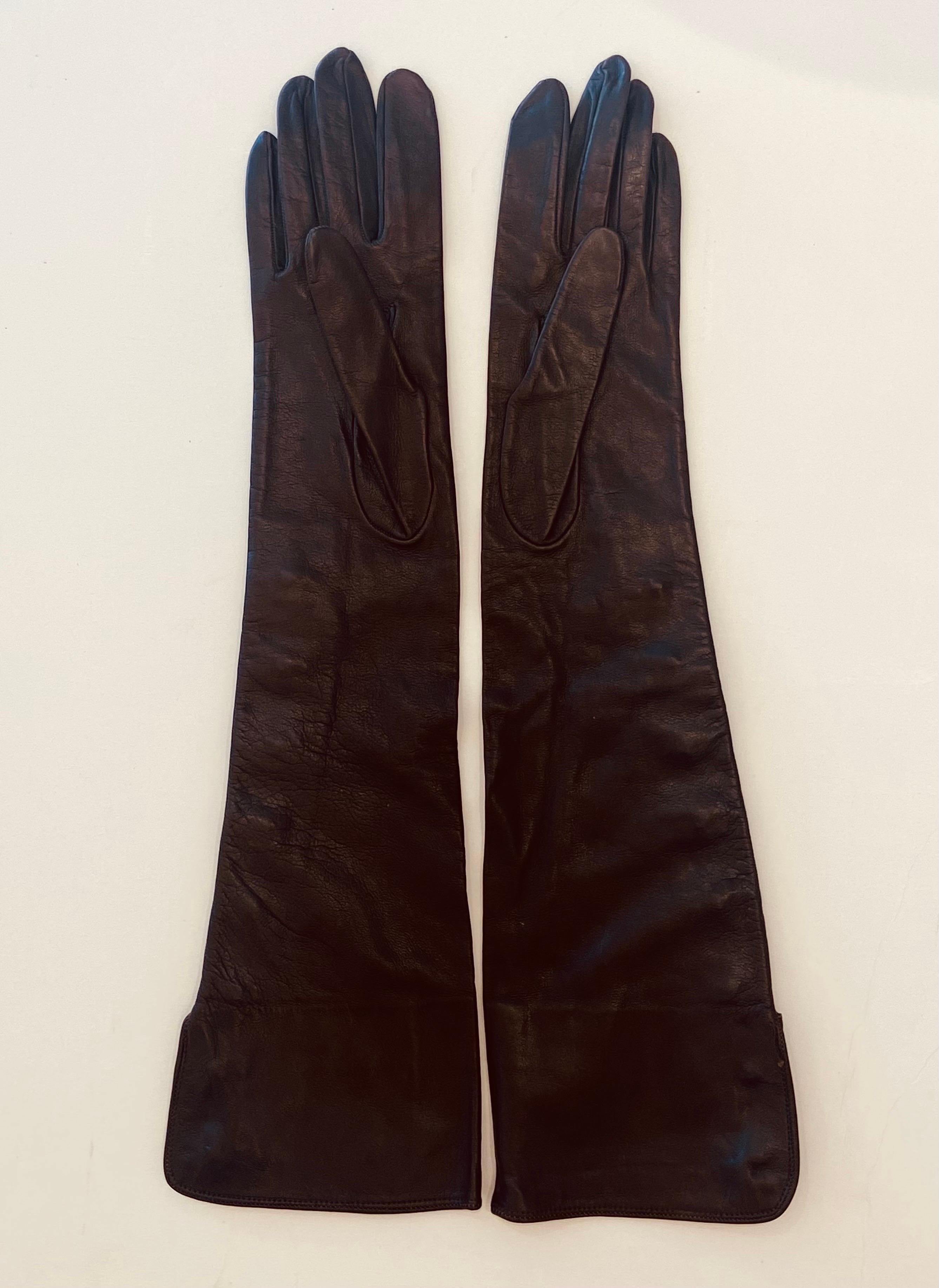 Chanel buttery soft chocolate brown lambskin leather 8 button elbow length gloves marked size 7.
These beautiful gloves are lined in off white silk, they look barely worn. The outside of each glove has 8 Chanel gold logo buttons, the 2 top buttons