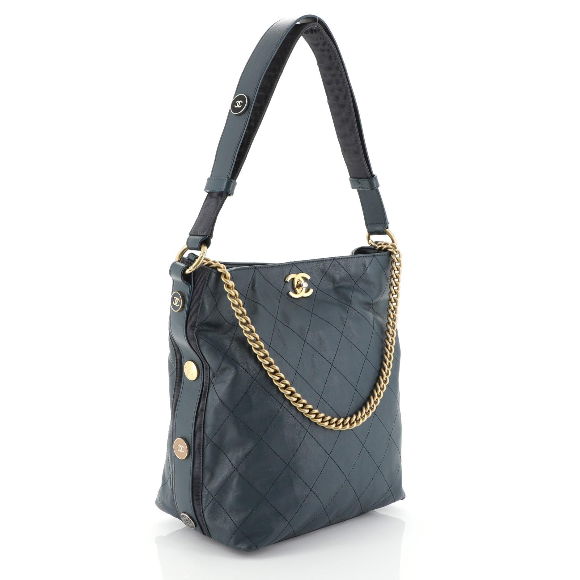 This Chanel Button Up Hobo Quilted Calfskin with Grosgrain Large, crafted from blue quilted calfskin with grosgrain, features chain link handle, flat shoulder strap, and matte gold-tone hardware. Its CC turn-lock closure opens to a blue fabric