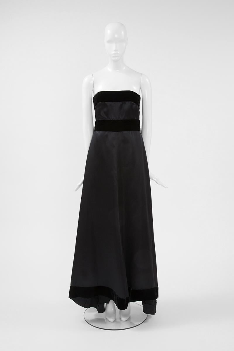 Féminine, intemporelle et élégante, trois mots qui résument parfaitement cette robe Karl Lagerfeld pour Chanel des années 80. Confectionnée en soie et laine noires, cette robe de soirée est ornée d'une large bande de velours noir, qui rehausse la