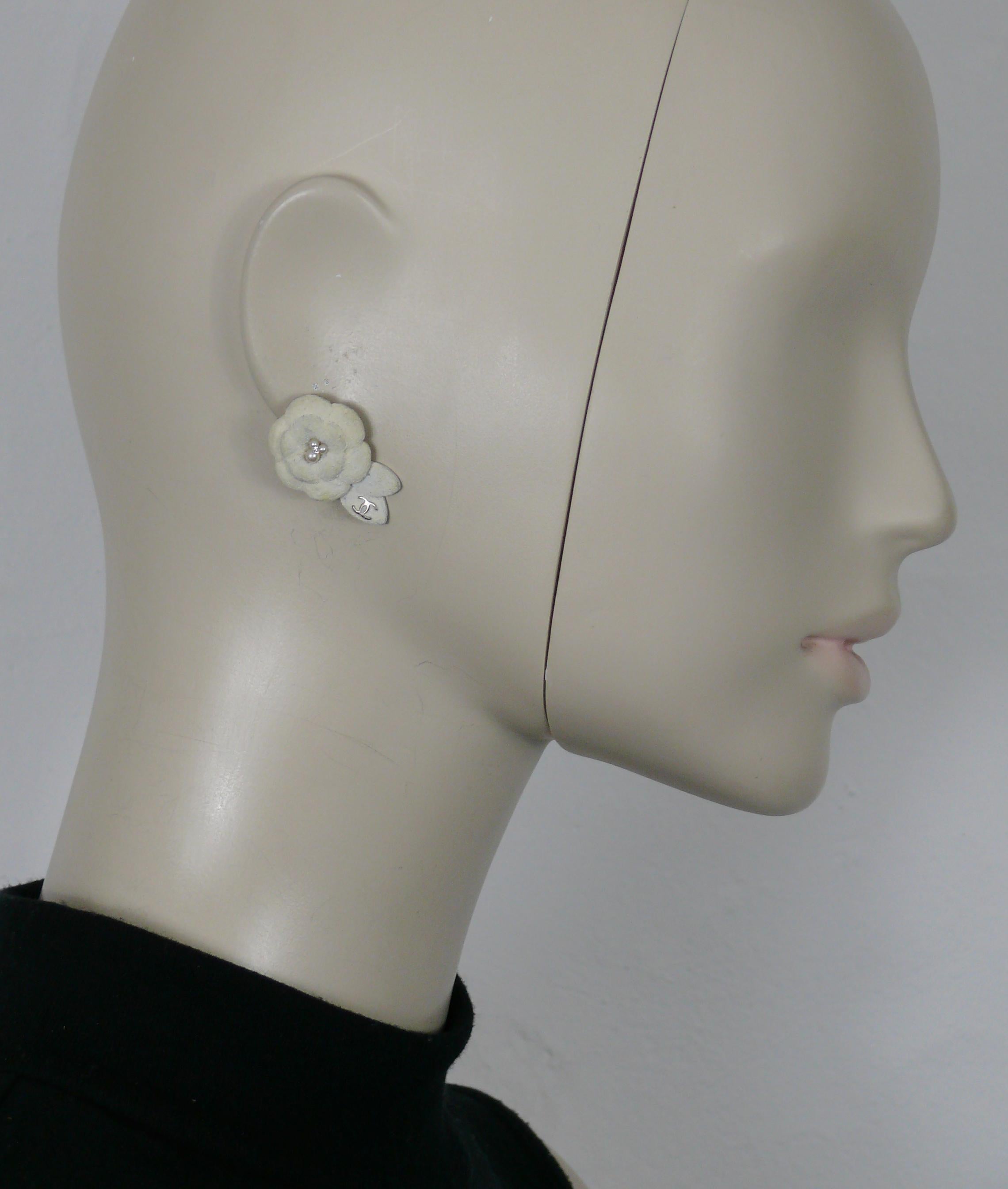 CHANEL by KARL LAGERFELD stud earrings featuring a textured off-white camellia flower with faux pearls and clear crystals at the center, CC logo on the leaves.

From the Fall 2005 Collection.

Embossed CHANEL 05 A Made in France.

Indicative