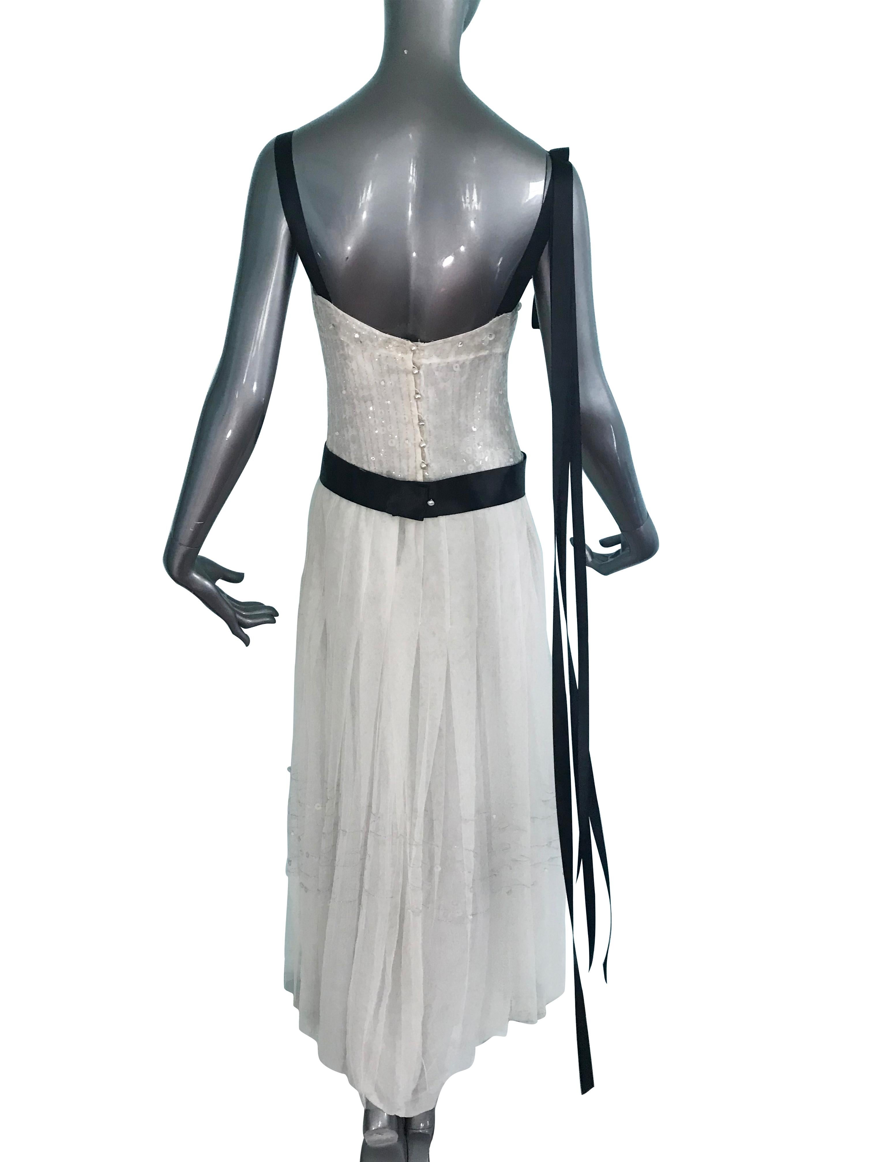 Chanel cruise 2005 collection white mesh evening dress embellished with white sequins and silver embroidery. A beaded, sweetheart neckline, black silk satin ribbon trim with signature CC interlocking logo.  Box pleating at the skirt and back pearl