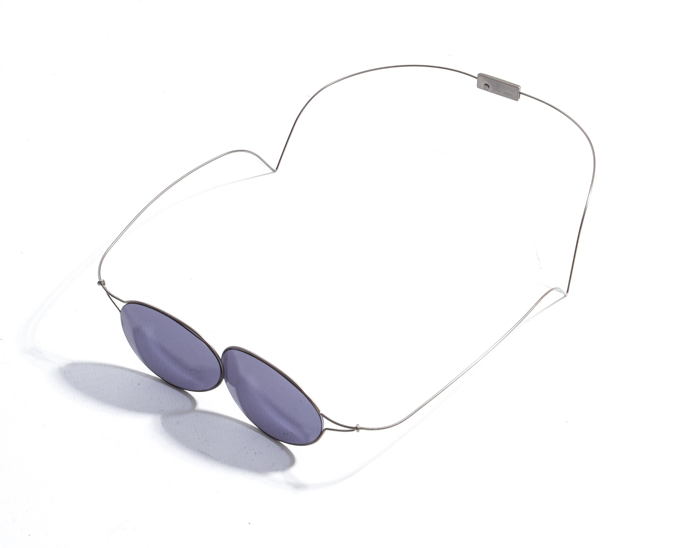 Chanel by Karl Lagerfeld; 'Double Monocle' sunglasses for sunbathing. Feather light, the wrap-around wire arms hug the head. Black monocle style lenses.

Spring-Summer 1999

'Some remain skeptical as to whether these groundbreaking sunglasses will