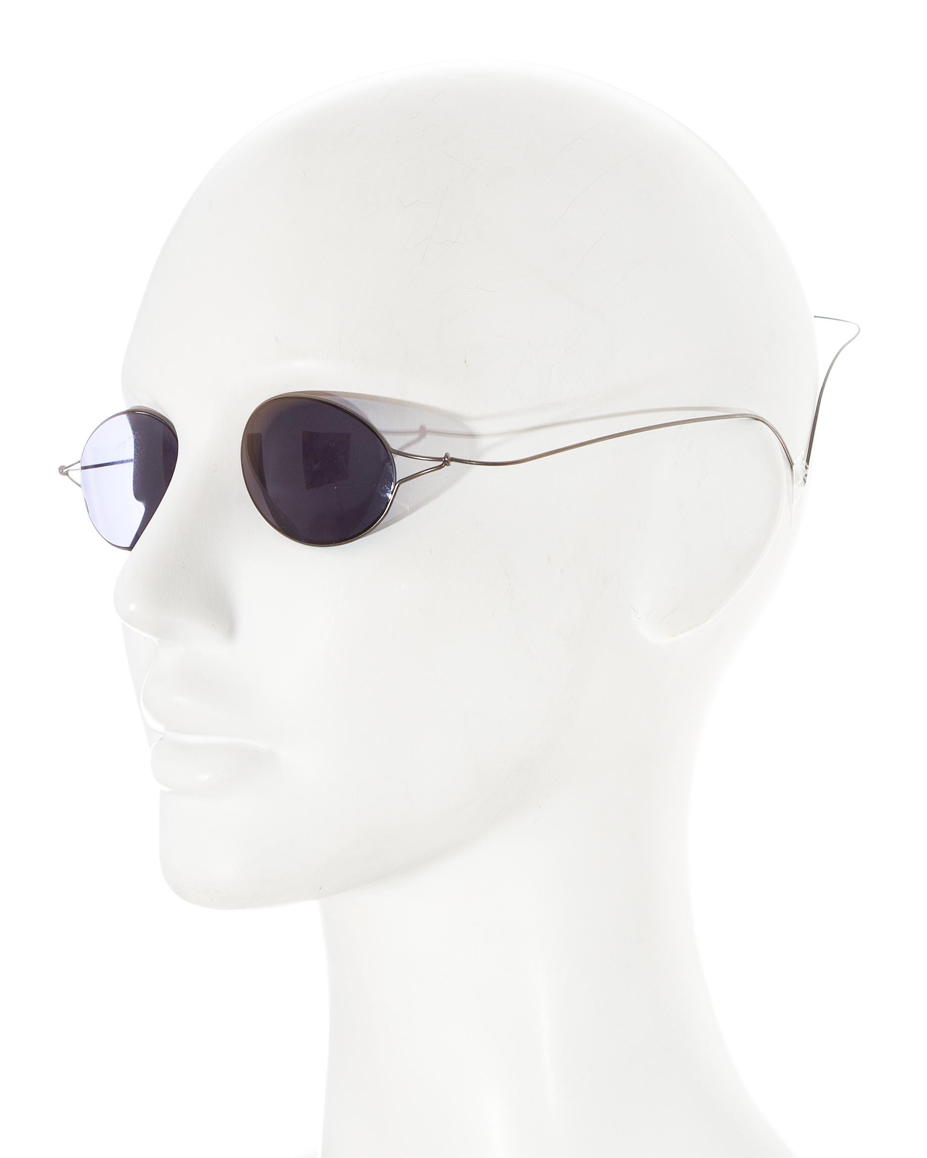 Chanel by Karl Lagerfeld; 'Double Monocle' sunglasses for sunbathing. Feather light, the wrap-around wire arms hug the head. Black monocle style lenses. 

'Some remain skeptical as to whether these groundbreaking sunglasses will really stay in place
