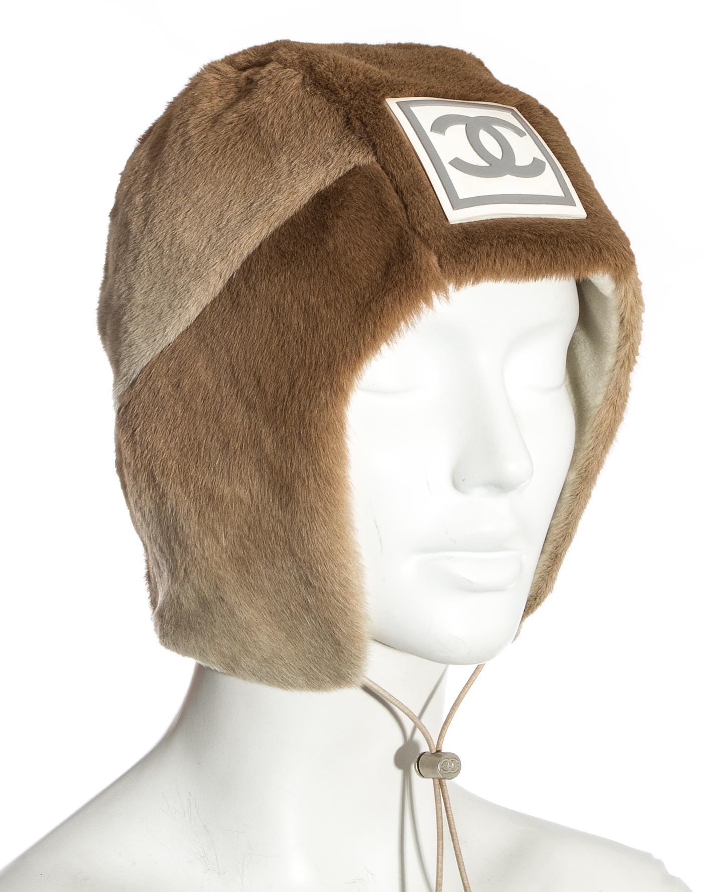 Chanel by Karl Lagerfeld; fawn sheared fur trapper hat. Large rubber interlocking C logo at the front, silver toggle drawstring fastening, cream fleece lining.

Fall-Winter 2001