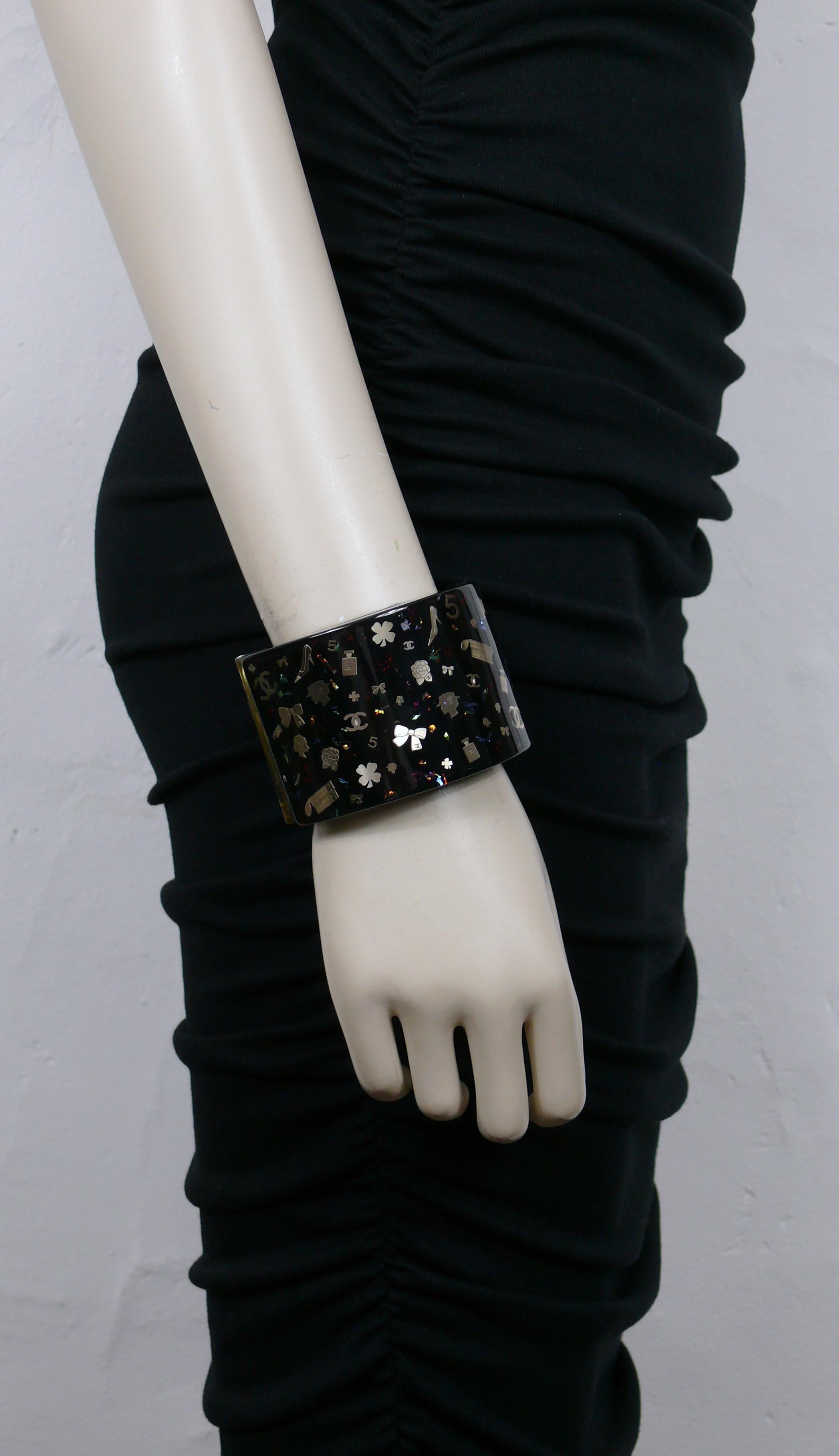 CHANEL by KARL LAGERFELD black cuff bracelet featuring iconic symbol inlaids : 5, CC logos, Coco Chanel profiles, perfume flacons, camellias, four-leaf clovers, quilted bags, pumps...

From the Fall 2006 Collection.

Clamp closure.

Embossed CHANEL