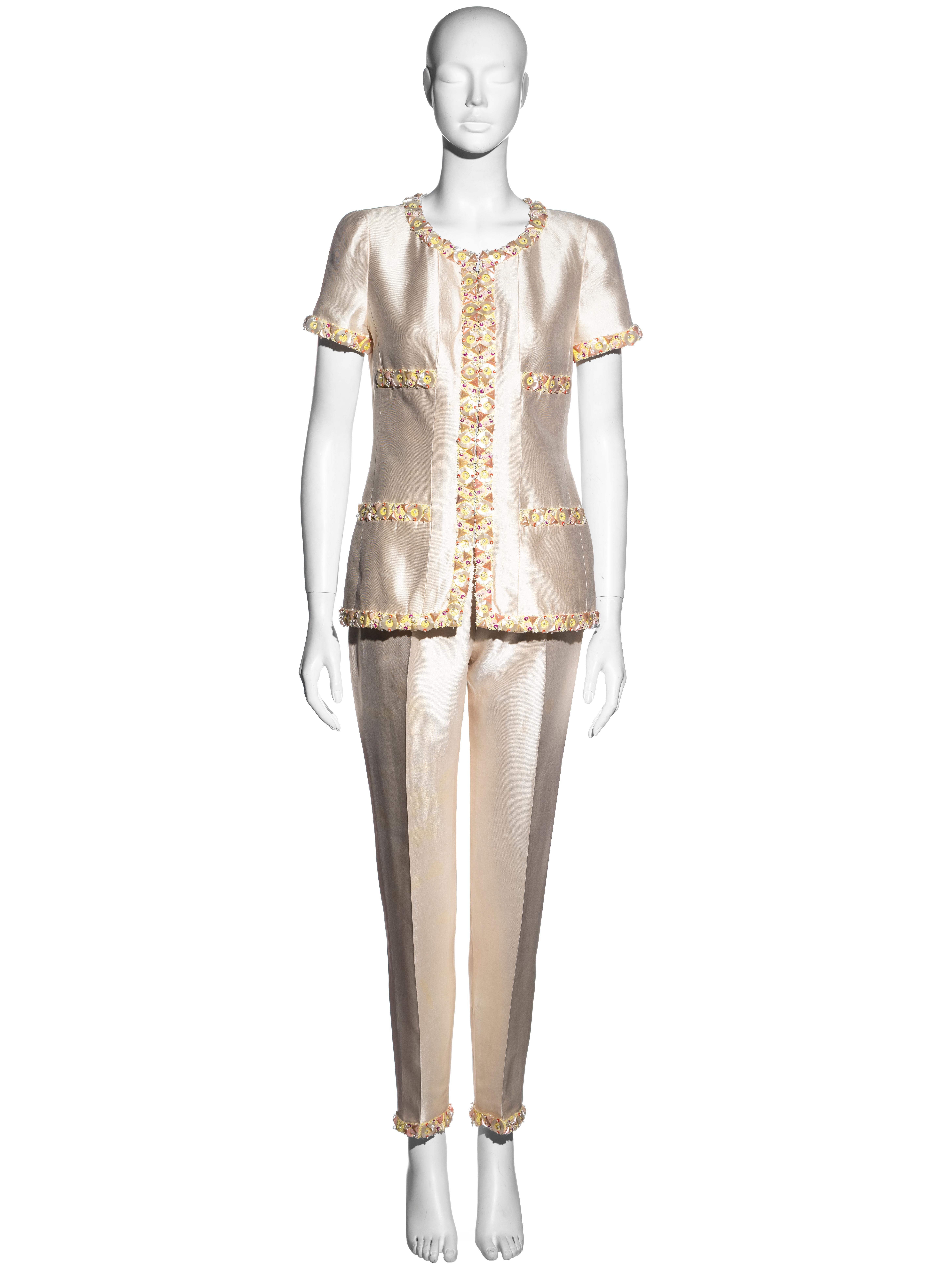 ▪ Chanel ivory silk evening pantsuit
▪ Designed by Karl Lagerfeld
▪ Short sleeve jacket with front zip fastening
▪ Embellished trim with yellow and pink sequined florals
▪ Matching straight-leg pants with ankle zips 
▪ FR 40 - UK 12 - US 8
▪