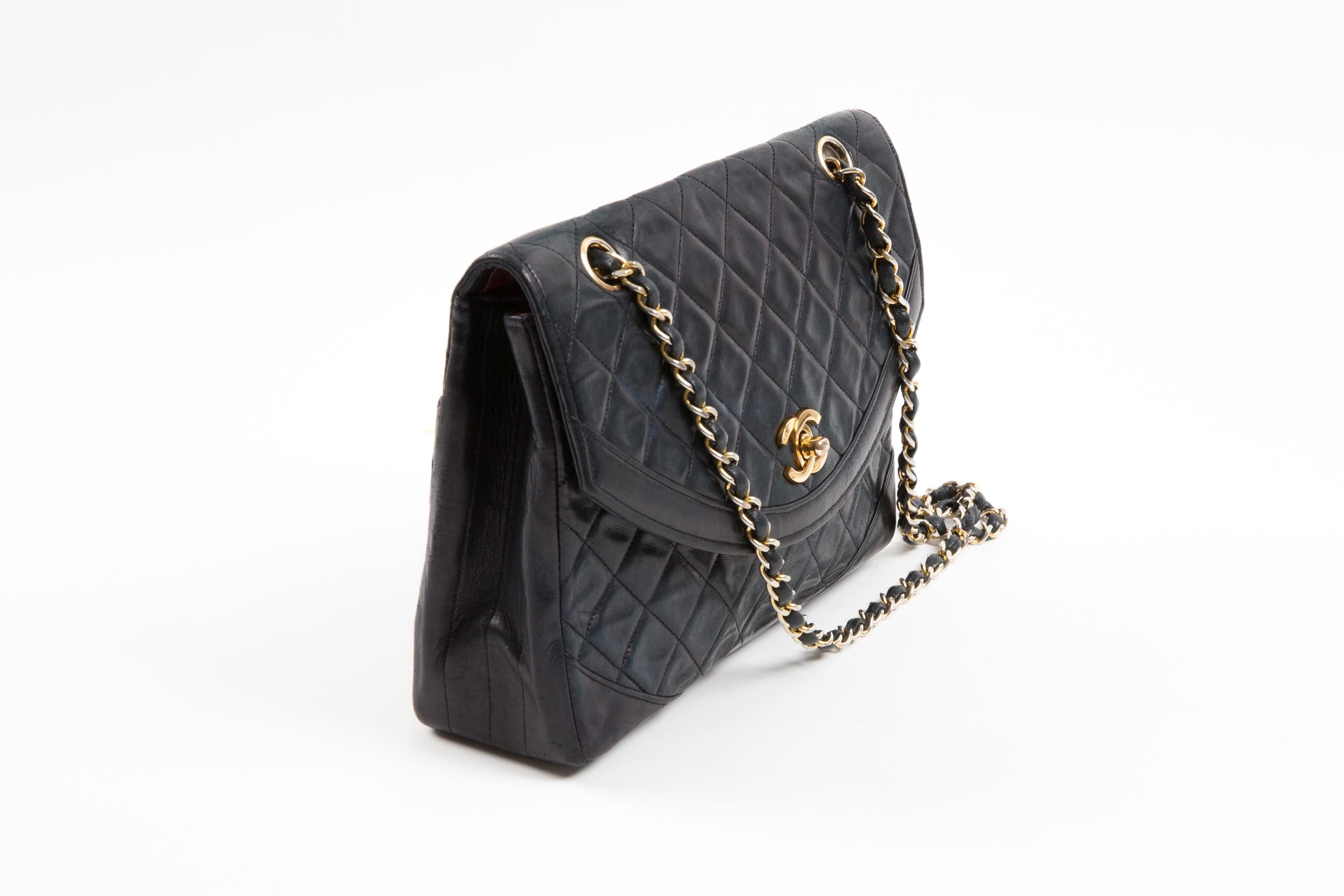 Chanel by Karl Lagerfeld navy quilted lambskin leather double flap bag featuring gold tone hardware with iconic CC turnlock closure, signature interwoven metal and leather shoulder/crossbody strap (29.5in. (75cm)), burgundy leather lining with two