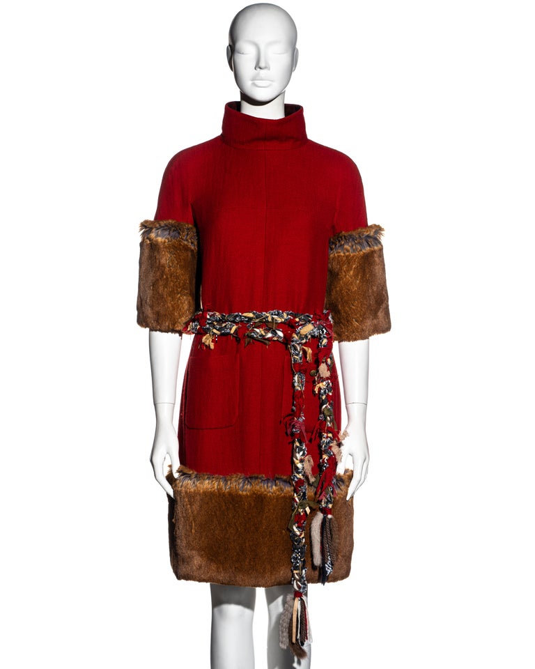 ▪ Chanel red cashmere wool knee-length dress
▪ Designed by Karl Lagerfeld 
▪ Faux 'fantasy' fur skirt and sleeves
▪ Funnel neck backed with brown lambskin leather
▪ Two front pockets 
▪ Braided ribbon belt with chains and mink fur 
▪ Silk lining 
▪