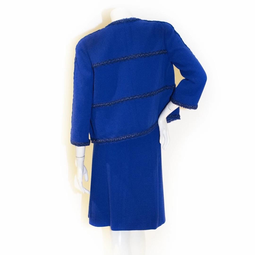 Chanel by Karl Lagerfeld Skirt Suit 
Fall / Winter 2007 
Made in France 
Royal Blue 
Braided detailing with copper tone lurex 
Two open pockets at waistline
Silver and blue clover buttons with rhinestones 
Open collar neckline 
Hemline of jacket has