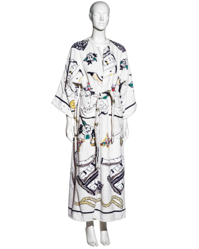 ▪ Chanel terry cloth robe
▪ Designed by Karl Lagerfeld 
▪ All over print features iconic Chanel designs illustrated by Karl Lagerfeld
▪ Two front pockets
▪ Matching belt ties at the waist
▪ Size Small - Medium
▪ Spring-Summer 1994