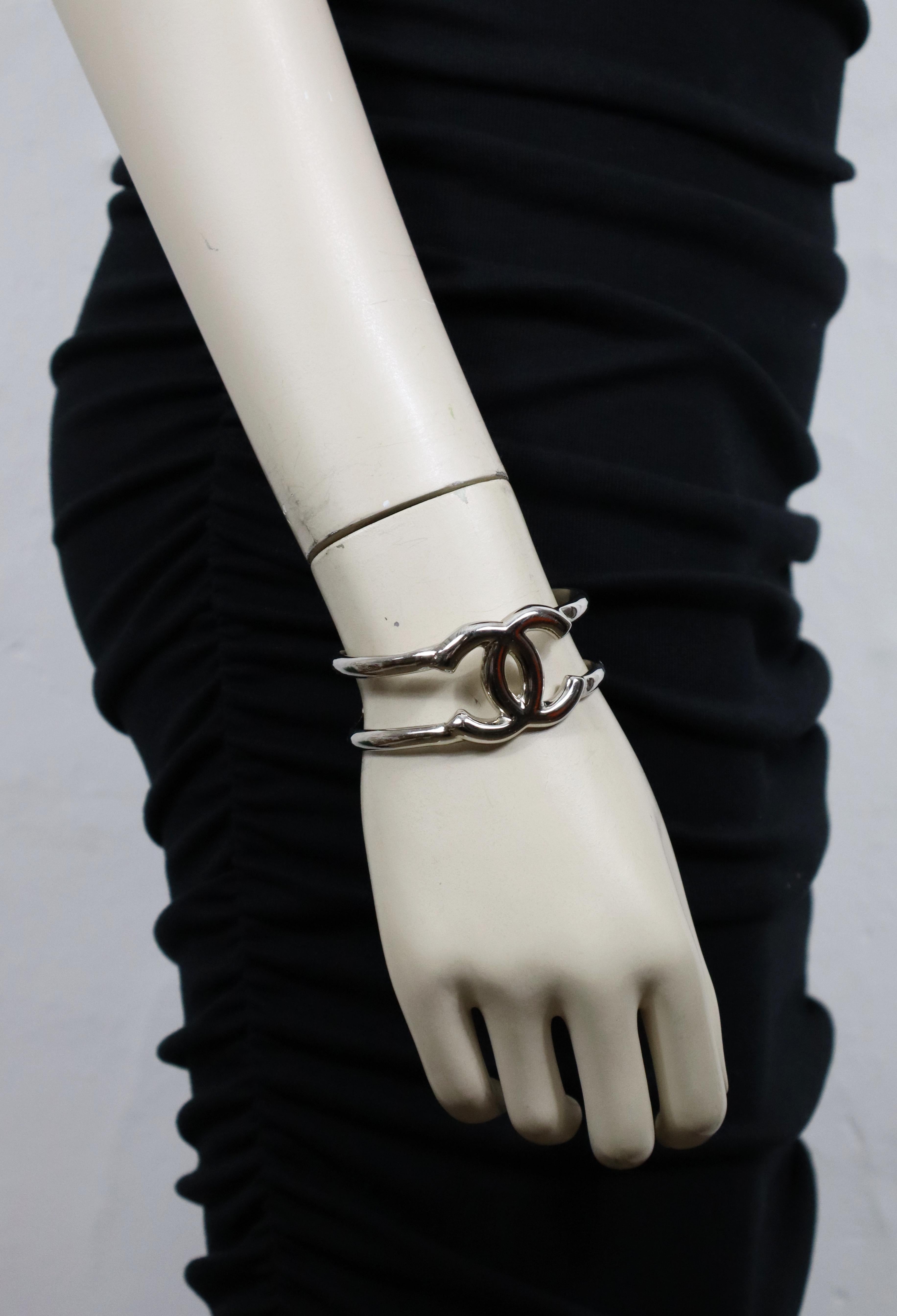 Bracelet manchette ajouré en ton argenté vintage CHANEL by KARL LAGERFELD avec logo CC au centre.

De la collection automne 1997.

Gaufrage CHANEL 97 A Made in France.

Mesures indicatives : dimensions intérieures environ 5,7 cm x 4,4 cm (2.24