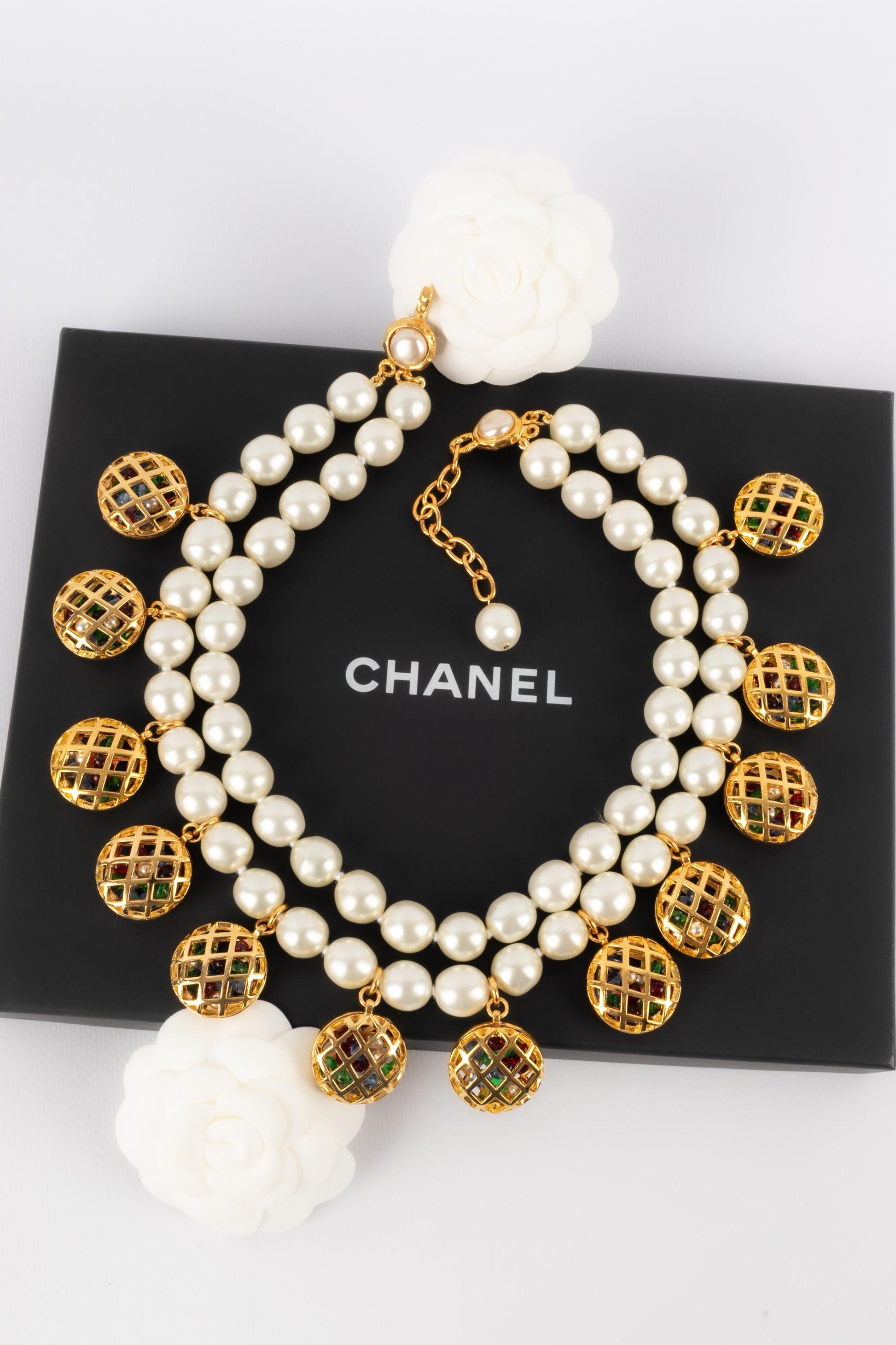 Chanel - (Made in France) Two-row costume pearl necklace with openwork golden metal charms holding multicolored glass paste pearls.

Additional information: 
Condition: Very good condition
Dimensions: Length: from 47 cm to 52 cm
 
Seller Reference: