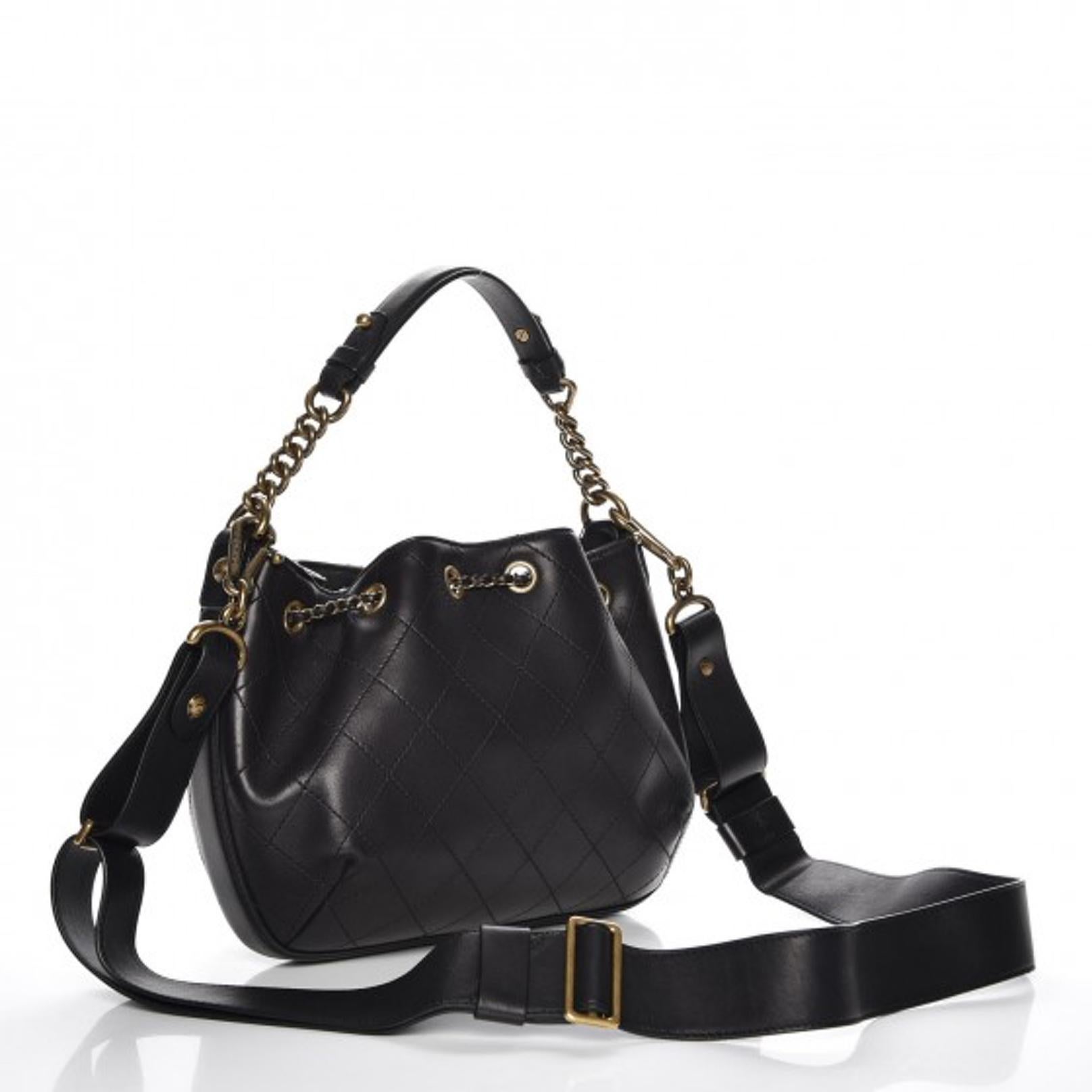 This hand bag is made with soft diamond stitched calfskin leather in black. The bag features a chain and leather top handle, an optional shoulder strap, aged gold hardware, drawstring closure and an interior with black microfiber with a zip and