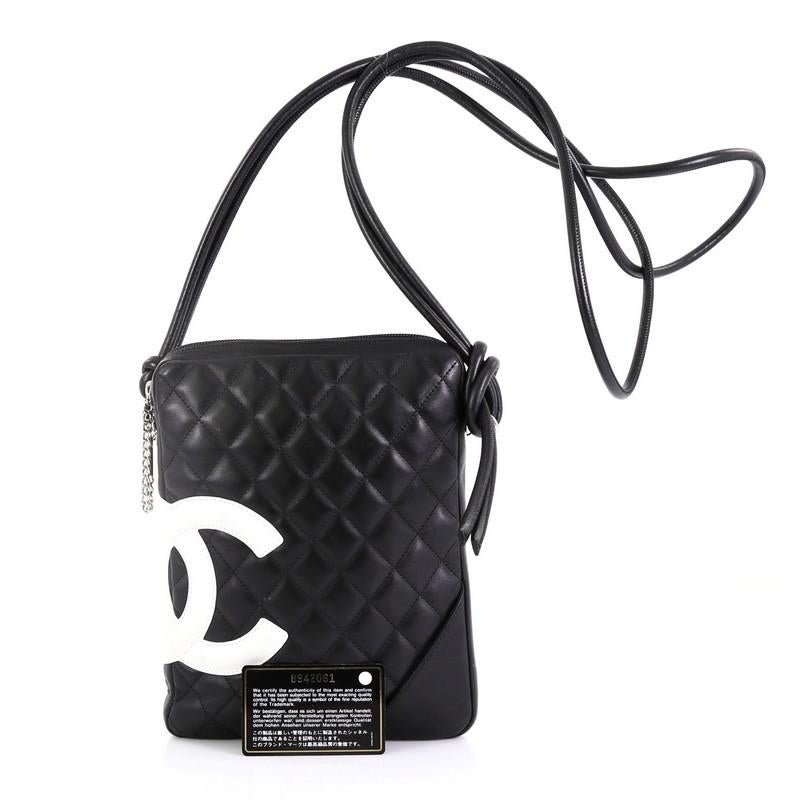 This Chanel Cambon Crossbody Bag Quilted Leather Medium, crafted from black quilted leather, features an interlocking CC side logo, dual rolled leather shoulder strap with knotted ends, and silver-tone hardware. Its zip closure opens to a pink
