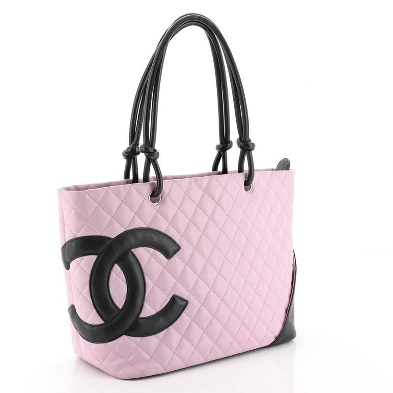 This Chanel Cambon Tote Quilted Leather Large, crafted from pink quilted leather, features large patent leather interlocking CC side logo, dual rolled leather handles with knotted ends, protective base studs, exterior back pocket and silver-tone