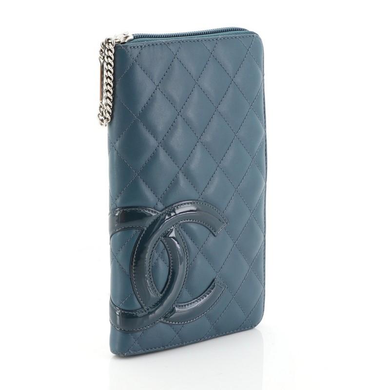 This Chanel Cambon Zip Around Organizer Quilted Lambskin, crafted from blue lambskin leather, features patent leather Chanel CC logo patch and silver-tone hardware. Its all around zip closures opens to a blue leather and gray fabric interior with