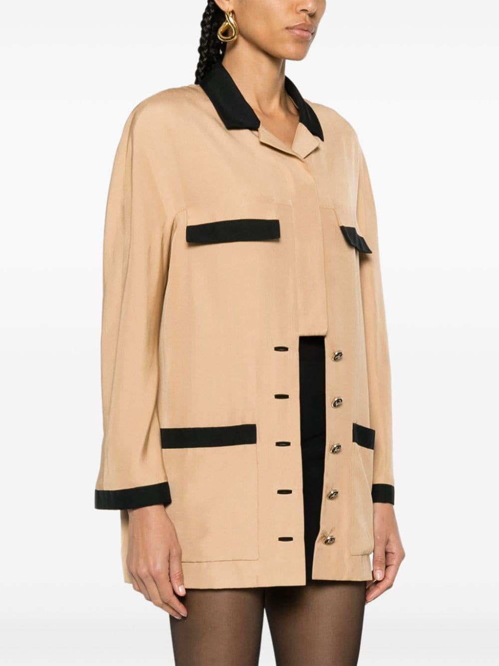 Chanel camel and black contrasting silk shirt jacket featuring contrasting trim, cuban collar, front button fastening, chest flap pockets, two front patch pockets, long sleeves and straight hem.
Composition: Silk 100%
Circa 1990s
Estimated size