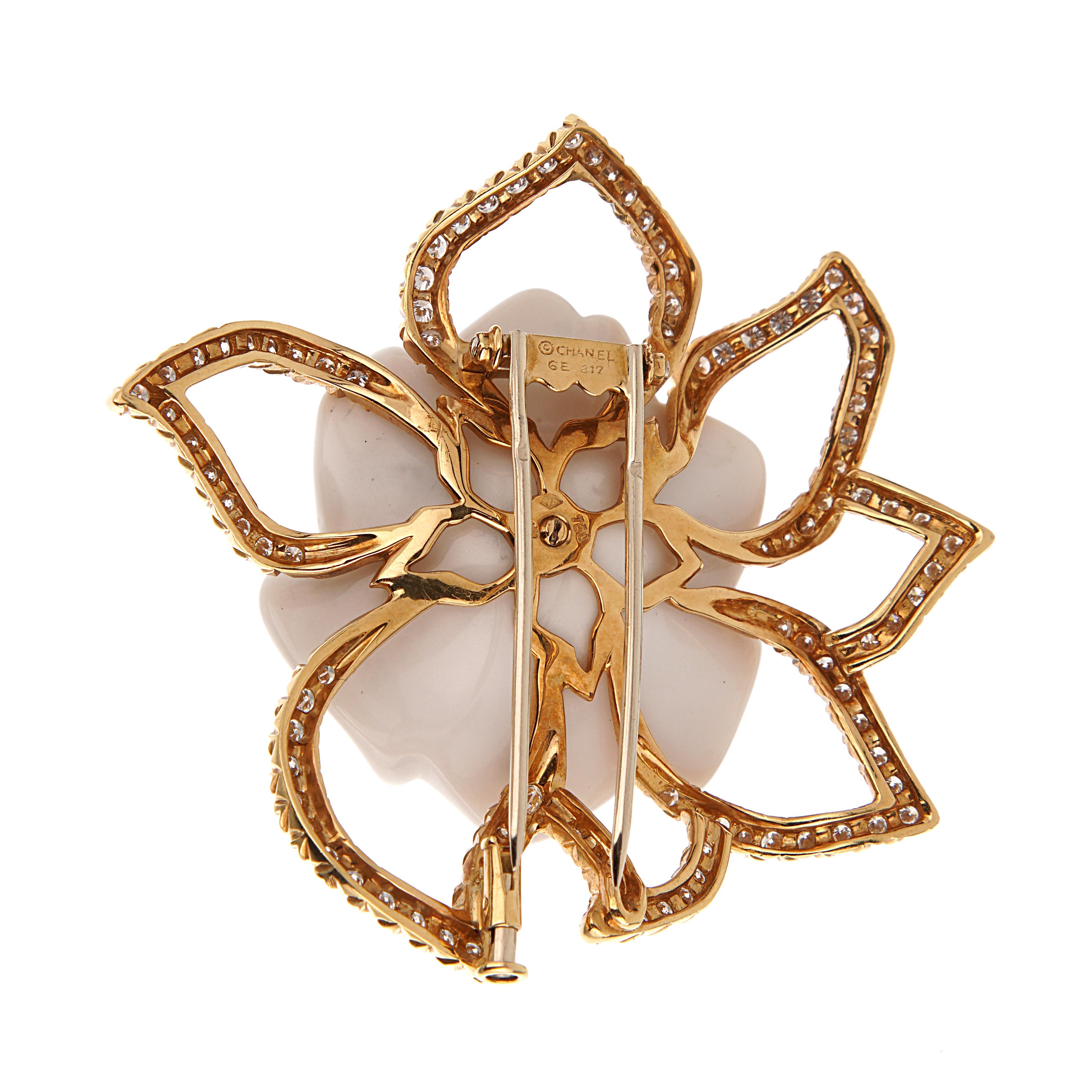 Le collier à pendentif broche Camelia de Chanel est un bijou polyvalent qui incarne le motif floral emblématique de la maison. Whiting, un camélia en agate blanche encadré d'or jaune 18 carats et de diamants taille brillant, peut être porté à la