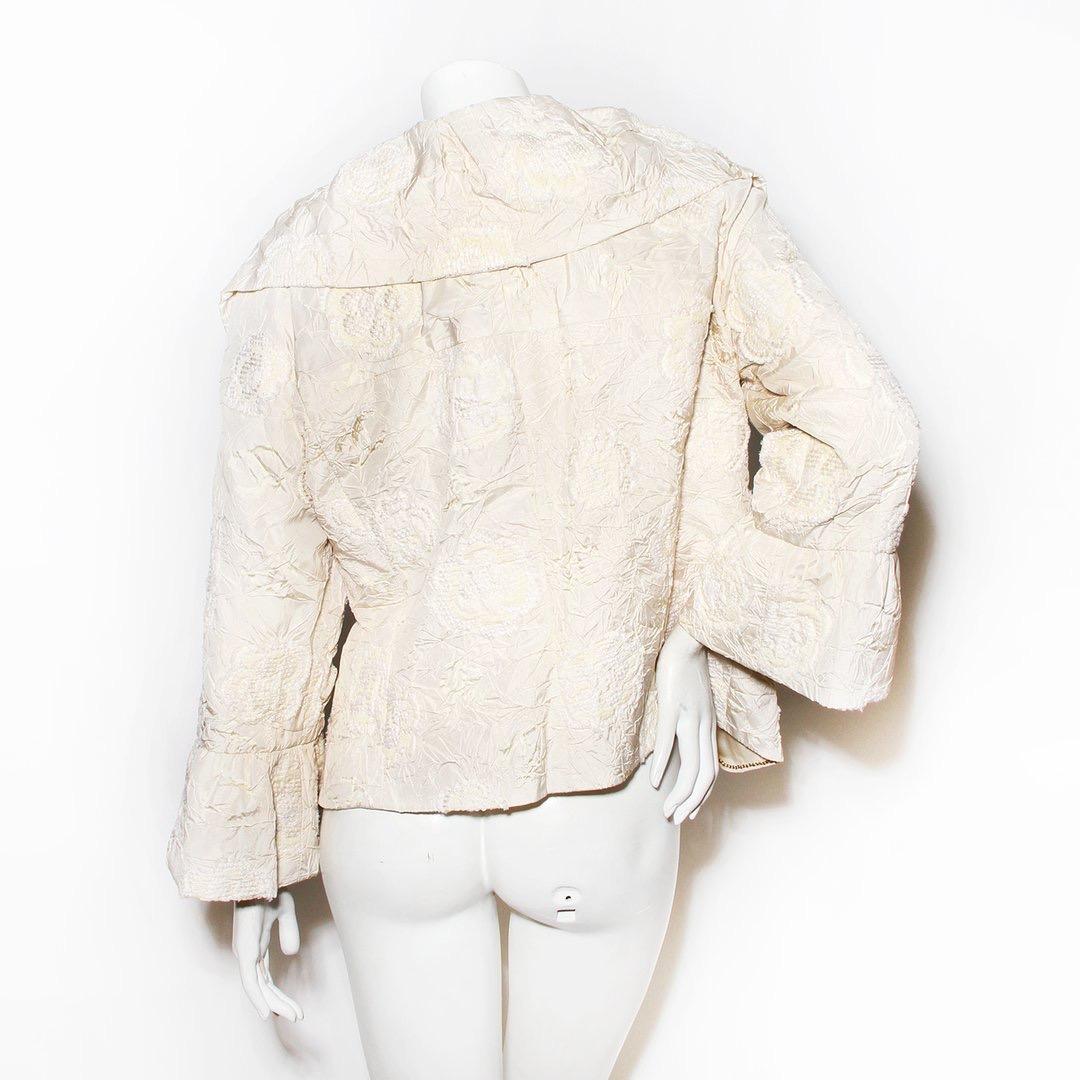 Camelia jacket by Chanel  
Spring 2006 RTW collection
Cream color 
Wide collar
Ruffle front 
Tie front closure 
Knit floral pattern
Puff sleeve 
Made in France
Condition: Excellent, little to no visible wear. (see photos) 
Size/Measurements: