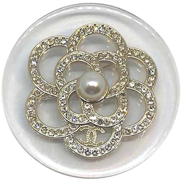 Easily worn with every outfit, this Spring 2018 collection Chanel pin is very versatile. It feature's Chanel's iconic camelia flower set with rhinestones and a central faux pearl set atop a clear lucite disk. It measures 2.15 inches in diameter.