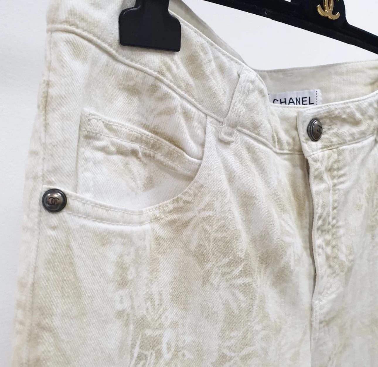 Élevez votre garde-robe avec ce magnifique pantalon en forme de jean de CHANEL ! Doté de l'emblématique imprimé Camélias beige sur fond écru, ce pantalon est emblématique de l'élégance intemporelle de Chanel. 

Détails :
- Deux poches à l'avant et à