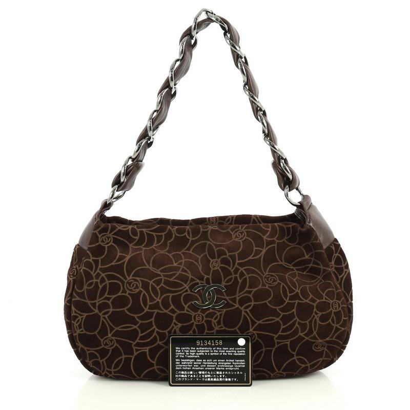 This Chanel Camellia Chain Shoulder Bag Embossed Suede Medium, crafted from brown suede, features woven-in leather chain strap, embossed camellia design, CC logo at front and gunmetal-tone hardware. Its zip closure opens to a brown fabric interior