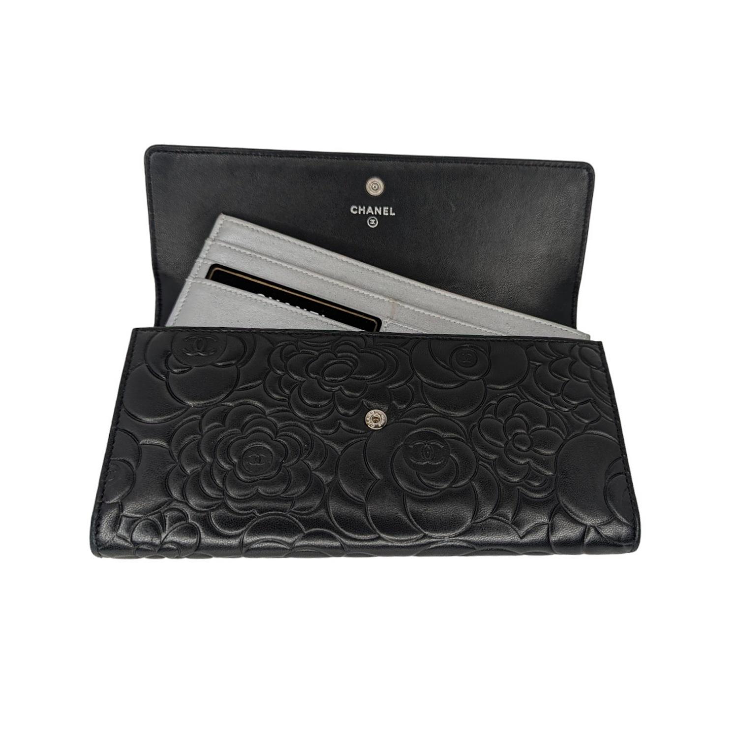 This chic wallet clutch is crafted of camellia embossed lambskin leather in black. It features a crossover flap with a polished silver interlocking CC logo, which opens to a silver leather interior with 6 card slots and removable flat insert with 6