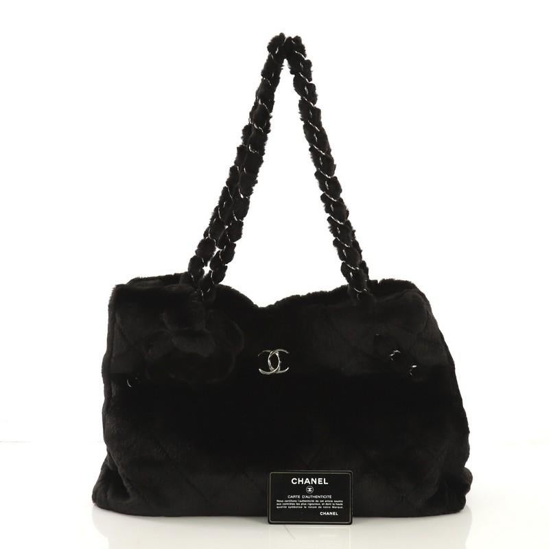 This Chanel Camellia Fantasy Tote Faux Fur Large, crafted from black faux fur, features woven-in faux fur chain straps, faux fur camellia embellishment at the front, and silver-tone hardware. It opens to a black fabric interior with side slip