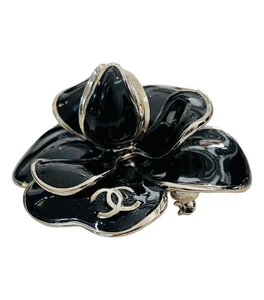 Chanel Broche logo « CC » en émail représentant une fleur de camélia
Broche noire en forme de fleur de camélia avec bordure argentée.
Le logo 