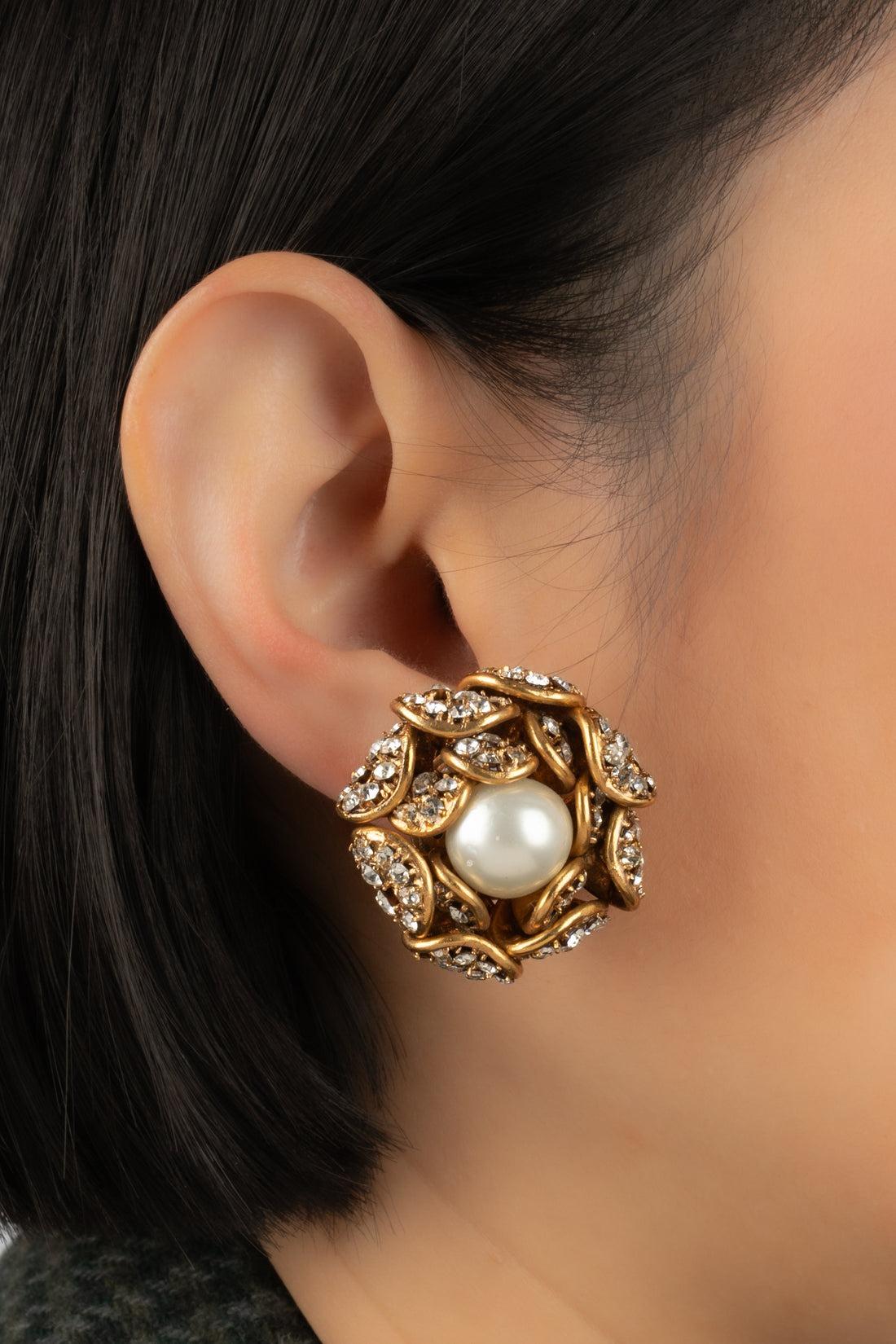 Chanel - (Made in France) Goldene Ohrringe aus Metall, verziert mit Strasssteinen und einem zentralen Perlencabochon.

Zusätzliche Informationen:
Zustand: Sehr guter Zustand
Abmessungen: Höhe: 4 cm

Sellers Referenz: BOB203