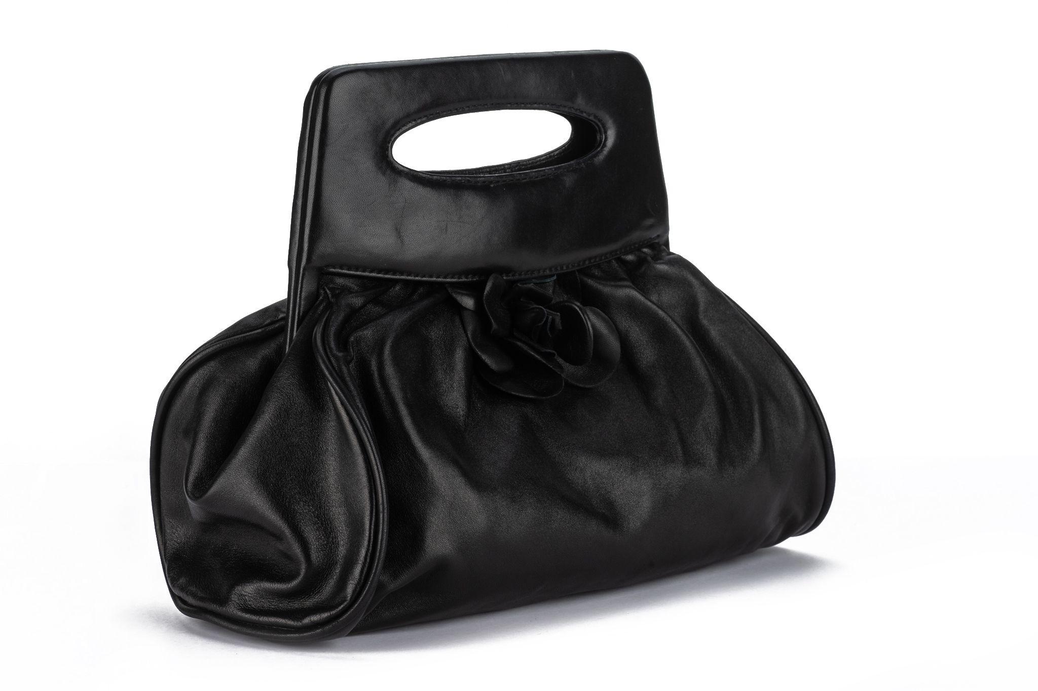 Chanel Camellia Top Handle Bag from the 2003-2004 Collection by Karl Lagerfeld. Features, black lambskin with a Camellia accent and gold-tone hardware. The cutout handles open up to logo jacquard lining  and a single interior pocket. Comes with