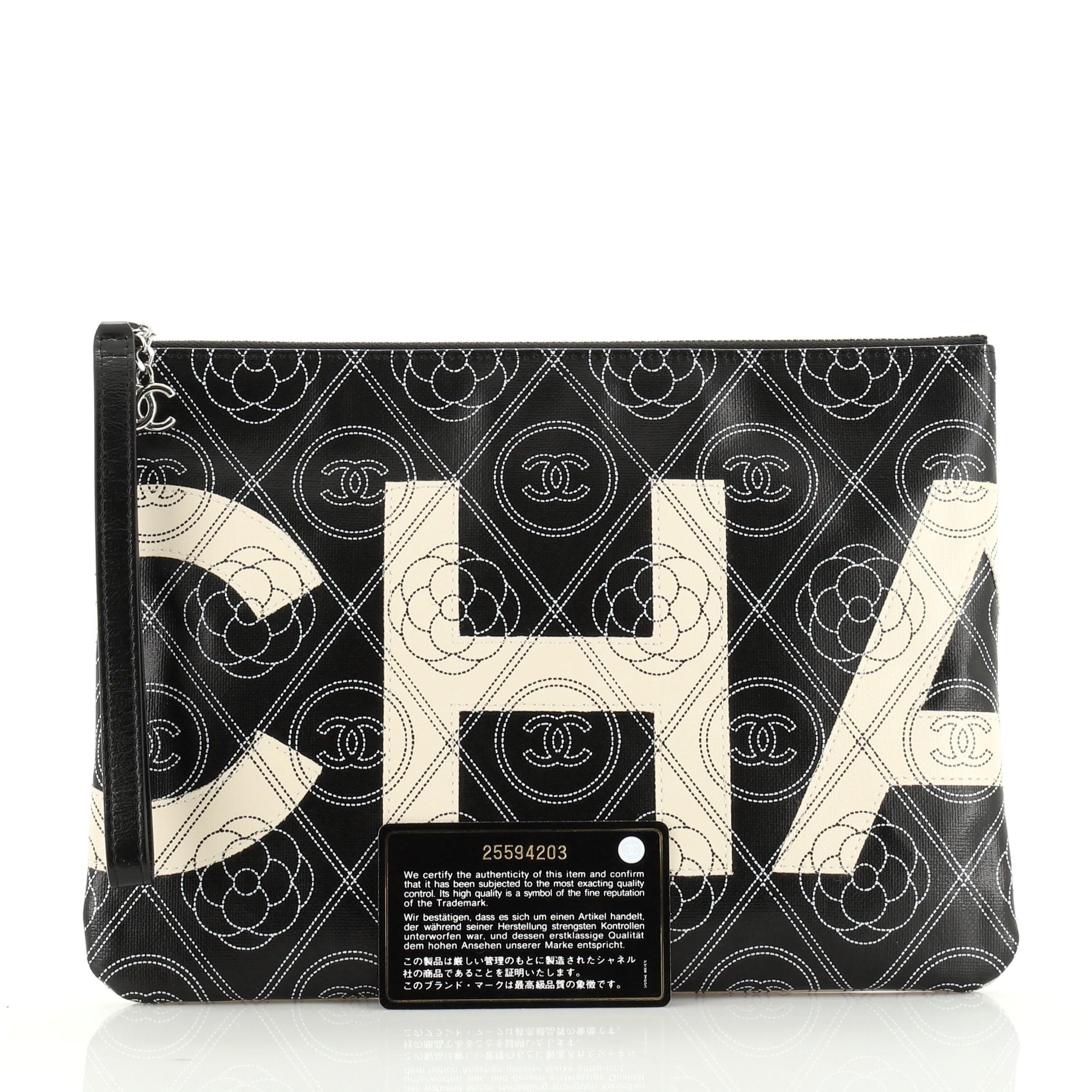This Chanel Camellia Logo Wristlet Clutch Printed Coated Canvas Large, crafted from black and white printed coated canvas, features a wrist strap and silver-tone hardware. Its zip closure opens to a black fabric interior. Hologram sticker reads: