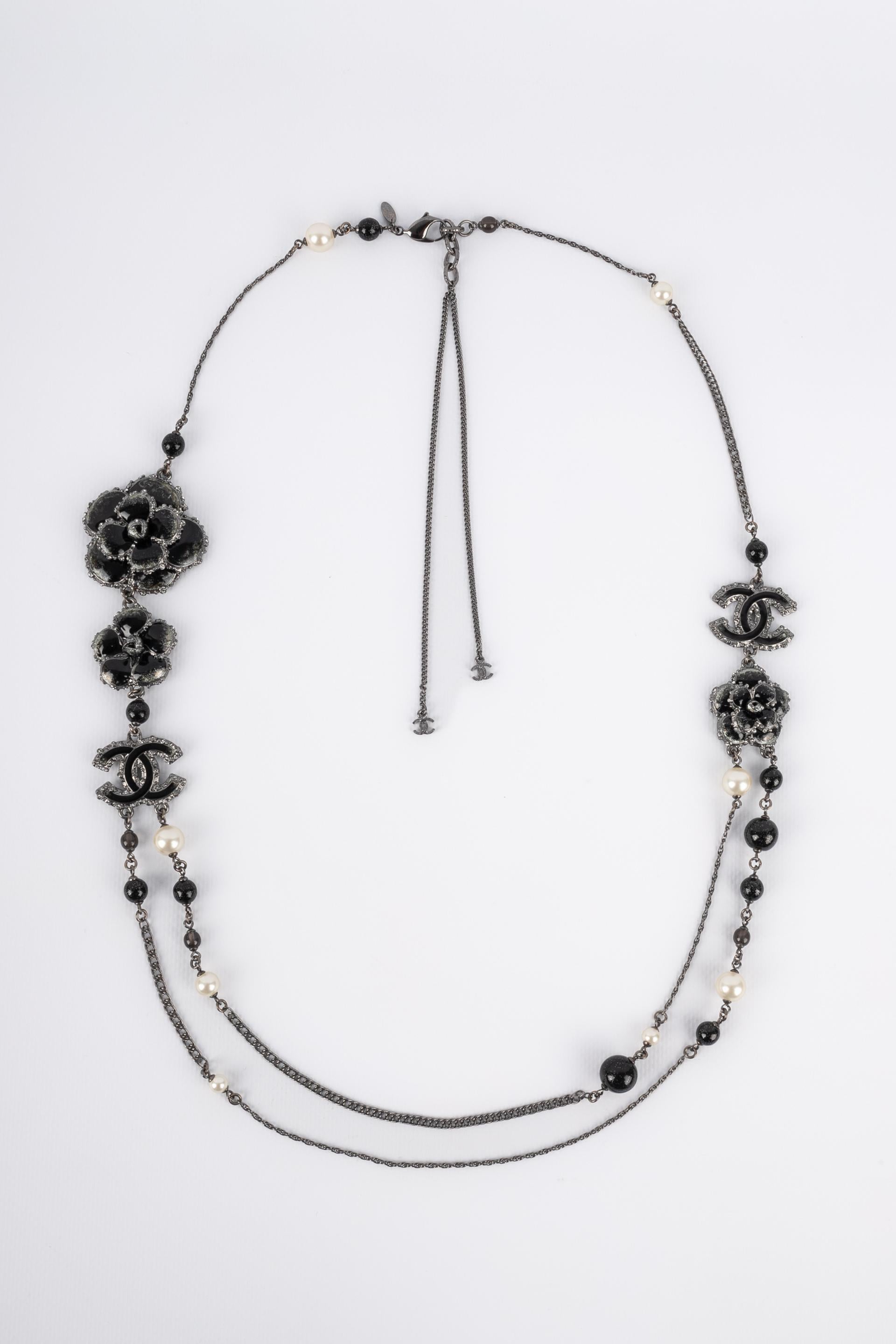 CHANEL - (Made in France) Dark-silvery metal long necklace with costume pearls, black glass pearls, camellias, and enameled cc logos. 2013 Collection.

Condition:
Very good condition

Dimensions:
Length: from 87 cm to 91 cm

CB99