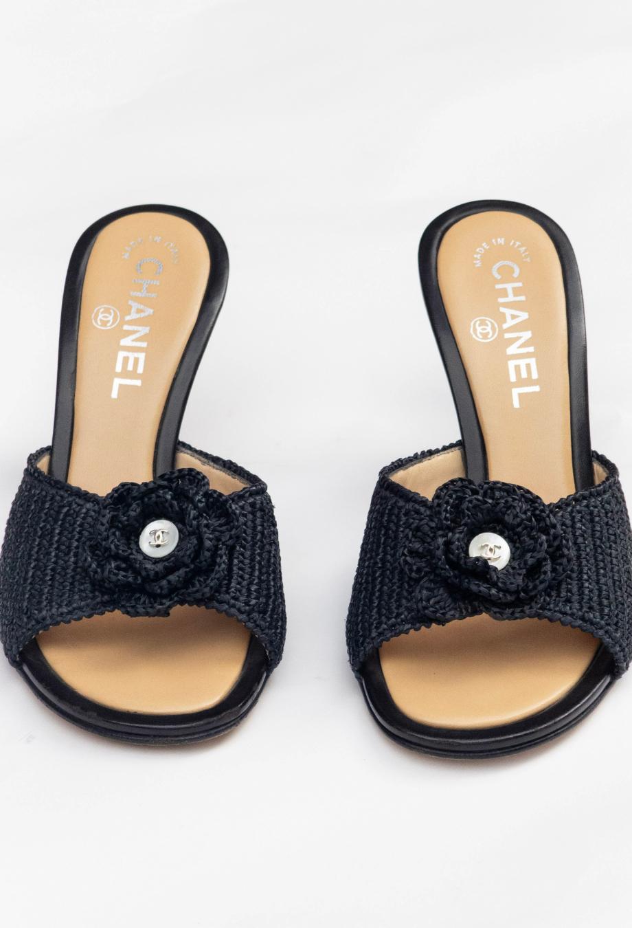 Chanel’s Camellia Raffia Heels capture the essence of effortless summer elegance through a distinctly Parisian lens. Crafted in Italy, they feature a meticulously woven raffia upper in deep navy-black, styled into an open-toe silhouette and adorned