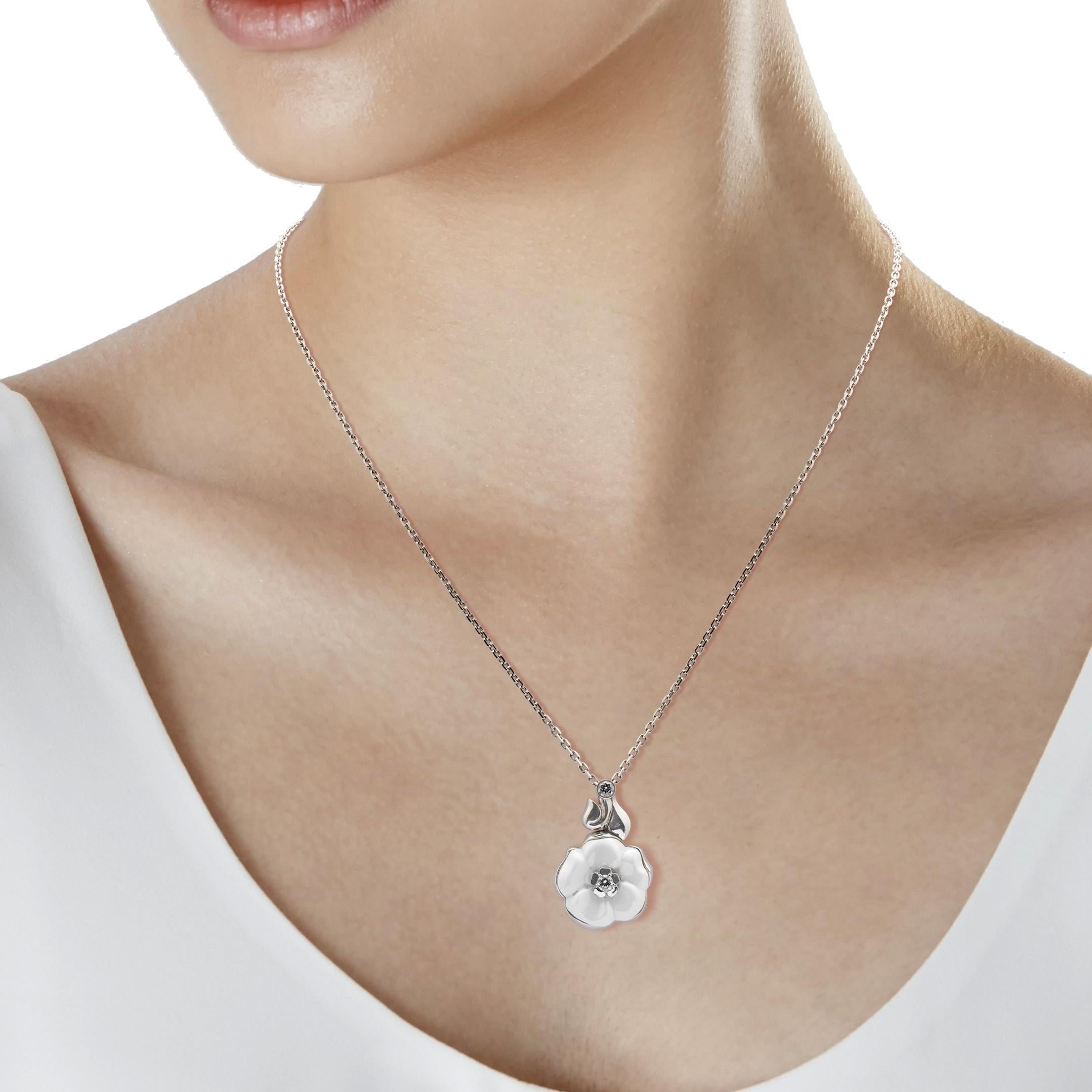 An iconic authentic Chanel Camellia necklace showcasing a white ceramic motif carved out of ceramic adorned with a round brilliant cut diamond in 18k white gold. The necklace measures 17 3/4