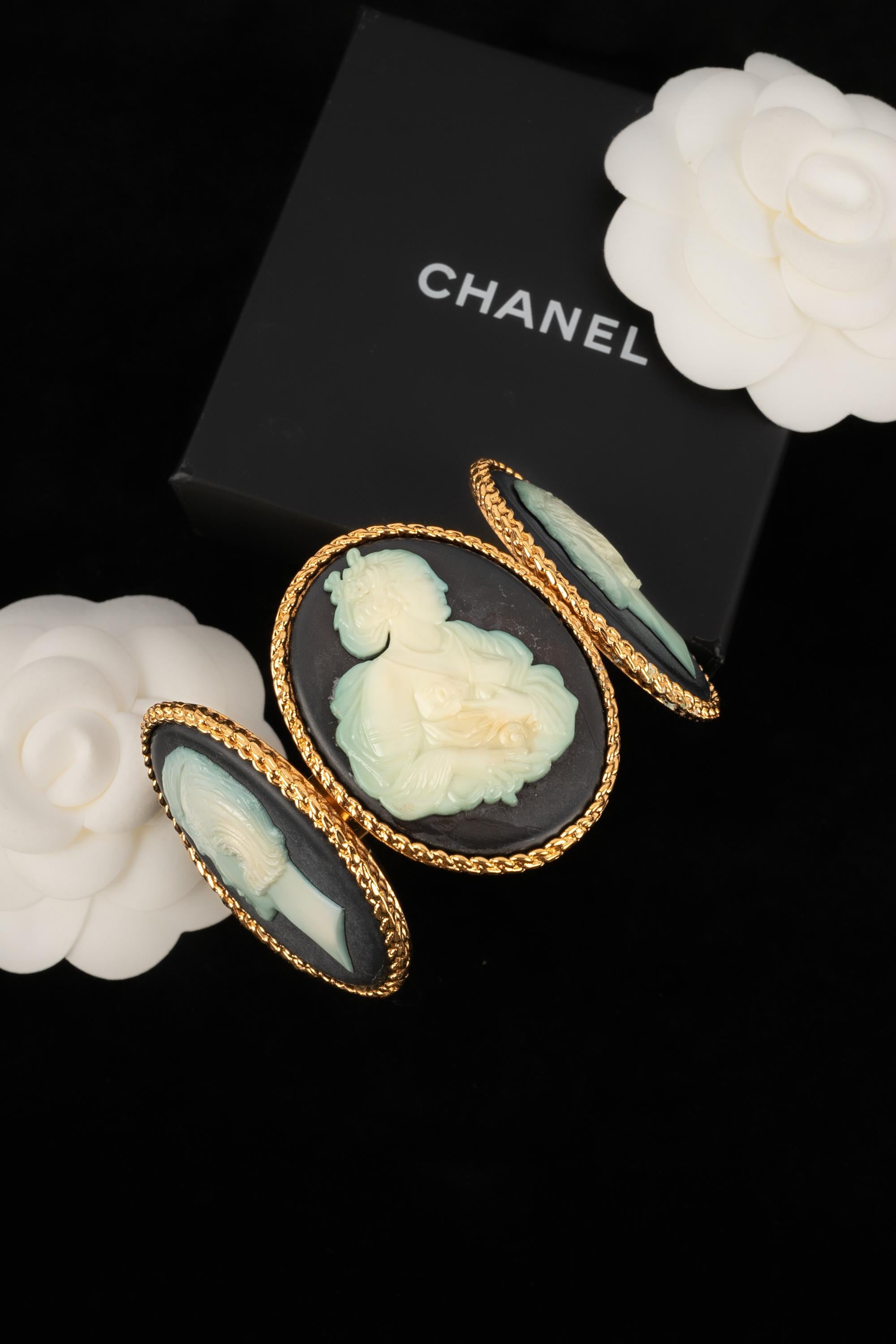 CHANEL - (Made in France) Pulsera de metal dorado decorada con camafeo. Colección Primavera-Verano 1989. Buen estado general, pero hay algo de decoloración en la parte blanca del camafeo.

Estado:
Buen estado

Dimensiones:
Longitud: 14,5 cm -